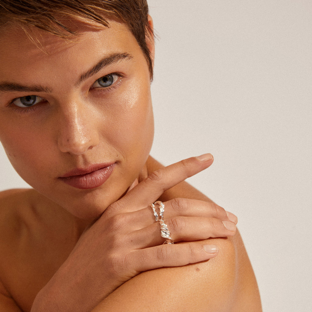 Close-up of a young person showcasing Pilgrim's STORM rings 3-in-1 set, featuring sculptural, twisted silver-plated rings on their fingers for a stylish, adventurous look.