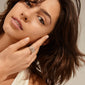ASPEN crystal ring gold-plated on woman's finger, featuring layered Preciosa crystals, showcasing its adjustable, recycled design in a close-up with her face.