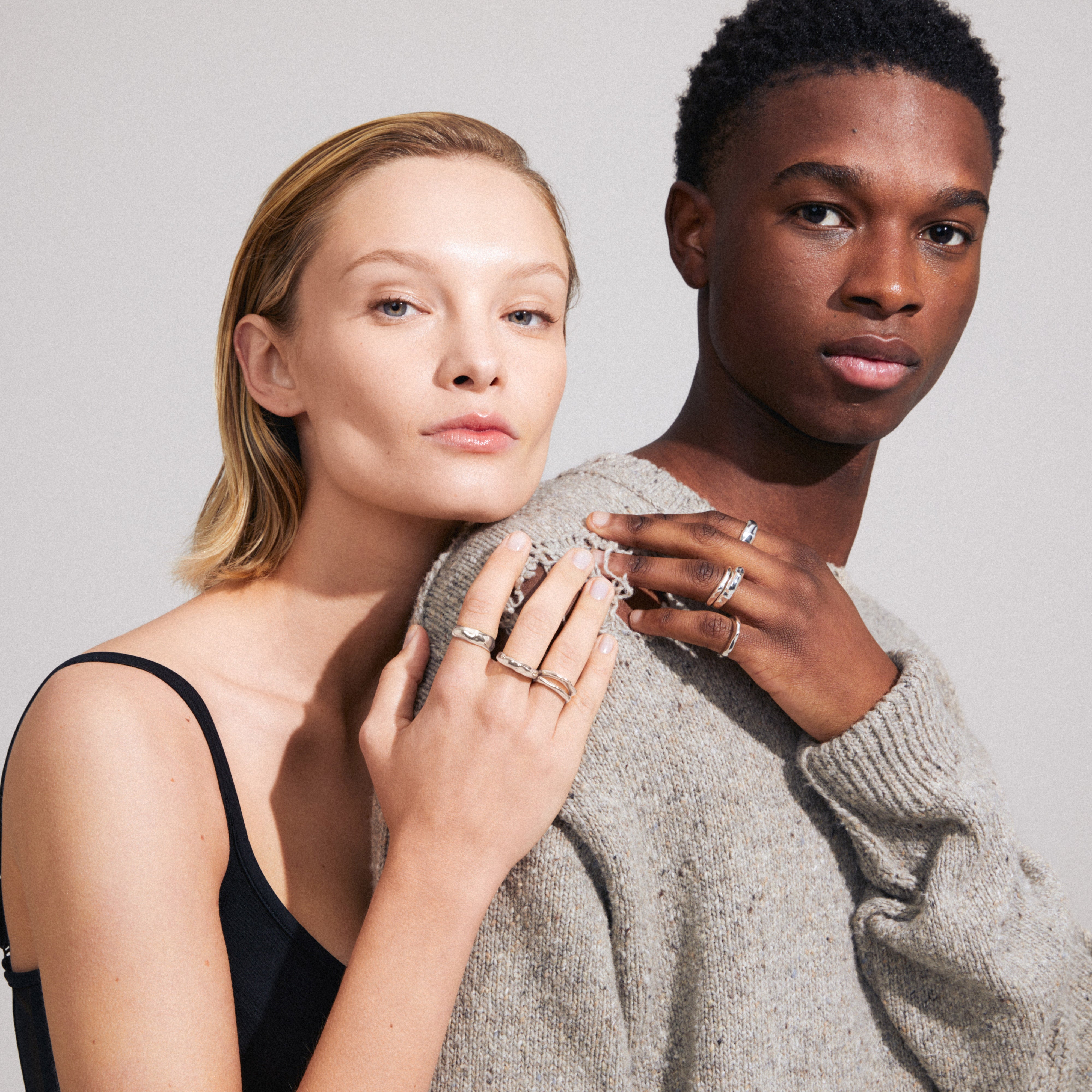 A woman elegantly showcases the ASHER rings 4-in-one set, silver-plated, emphasizing their wavy design and stylish, adjustable stacking appeal.