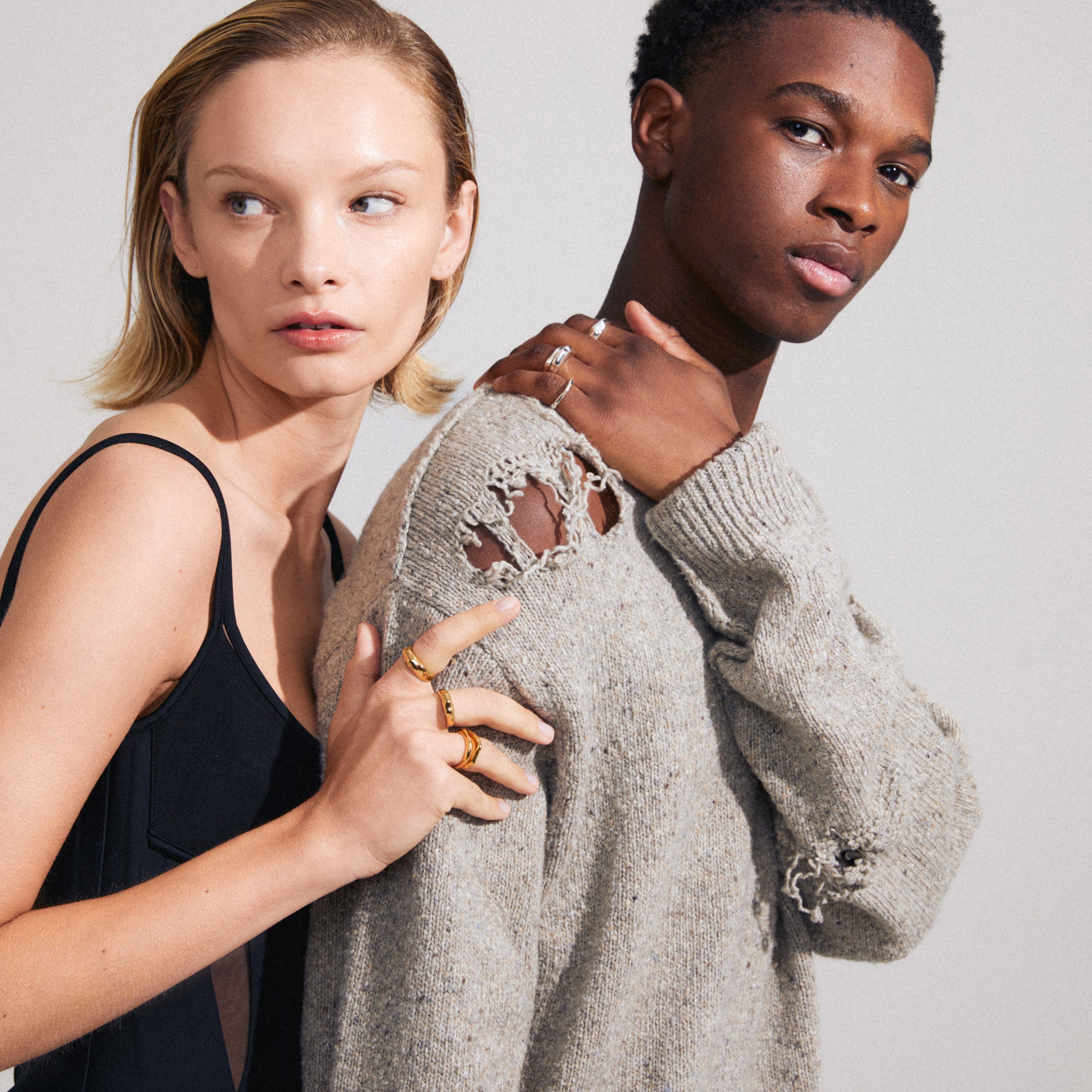 Man and woman showcasing Pilgrim's ASHER rings set, featuring four adjustable, silver-plated rings with wavy designs for a stacked, stylish look.