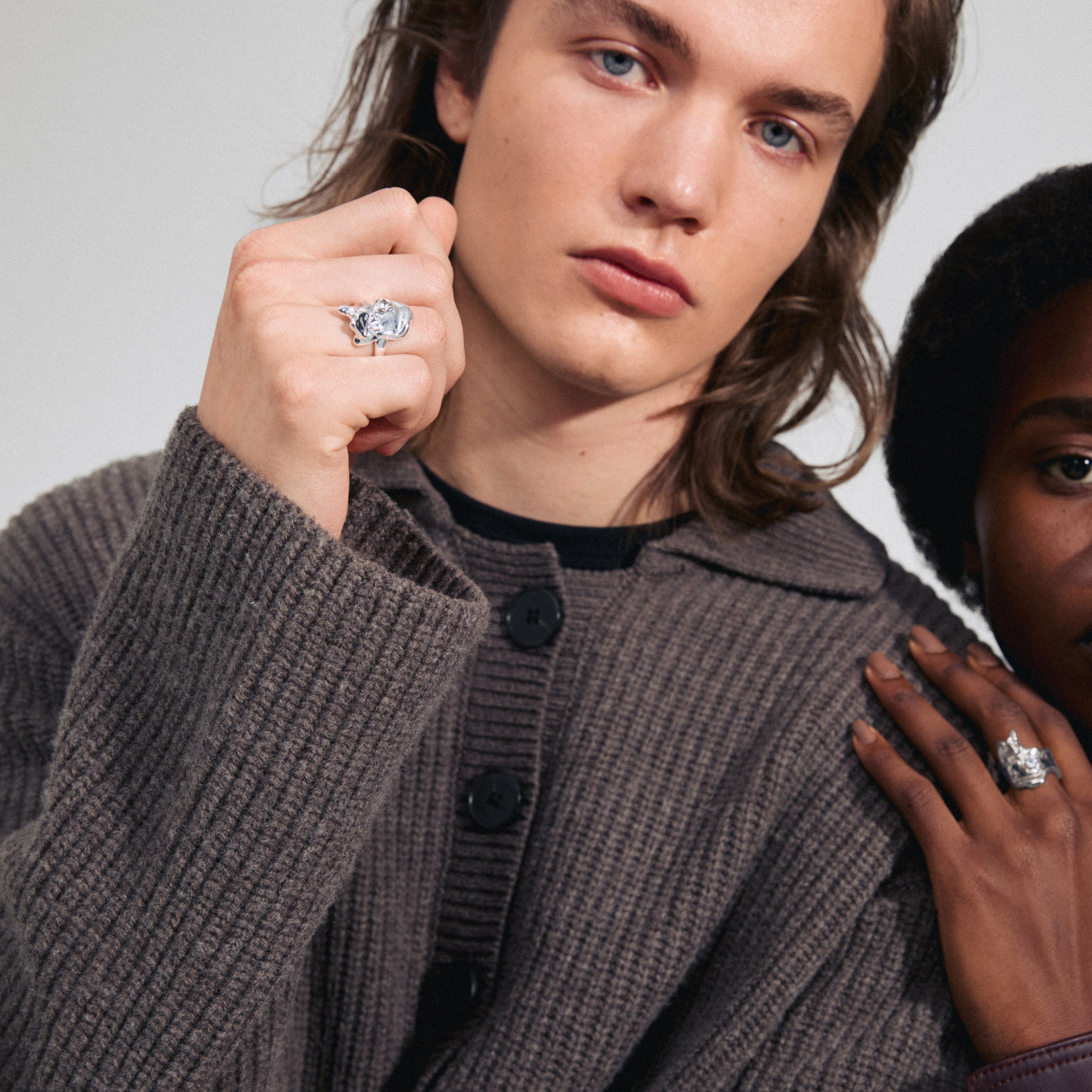 GIA crystal ring, silver-plated, with organic design and sparkling Preciosa crystal, held by a man with long hair, wearing a sweater.