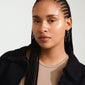 Close-up of a woman wearing WYATT gold-plated hoop earrings with a wavy design, highlighting their sleek, handcrafted appearance.