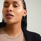 WYATT gold-plated earrings featuring a sleek, wavy design, worn by a woman with braided hair and earrings, highlighting Pilgrim's handcrafted style.