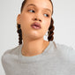 Young woman wearing Pilgrim's LARKIN earrings, gold-plated with a wavy silhouette, showcasing their minimalist yet impactful design against a softly lit background.