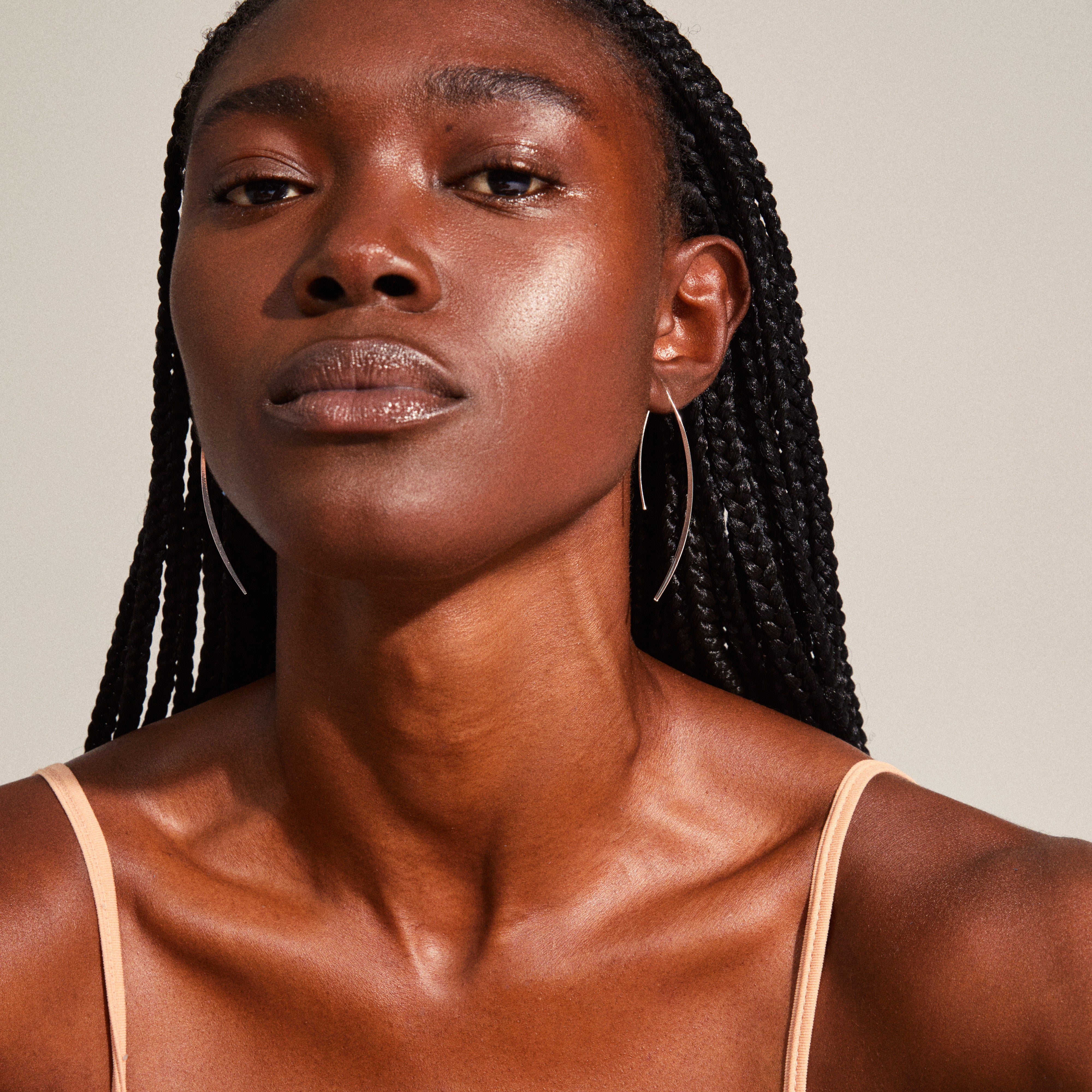 GRACE earrings silver-plated on a woman with long black braids; sculptural, angular design offering a modern twist on classic hoops, exuding elegance and refinement.