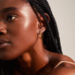 Close-up of a woman wearing NAJA twisted hoop earrings, gold-plated, showcasing their elegant twisted design and light-catching details.