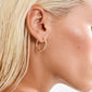 APRIL small hoop earrings gold-plated, shown on ear with bleached hair tucked behind, highlighting their smooth, elegant design. Ideal for versatile styling and sustainable fashion.