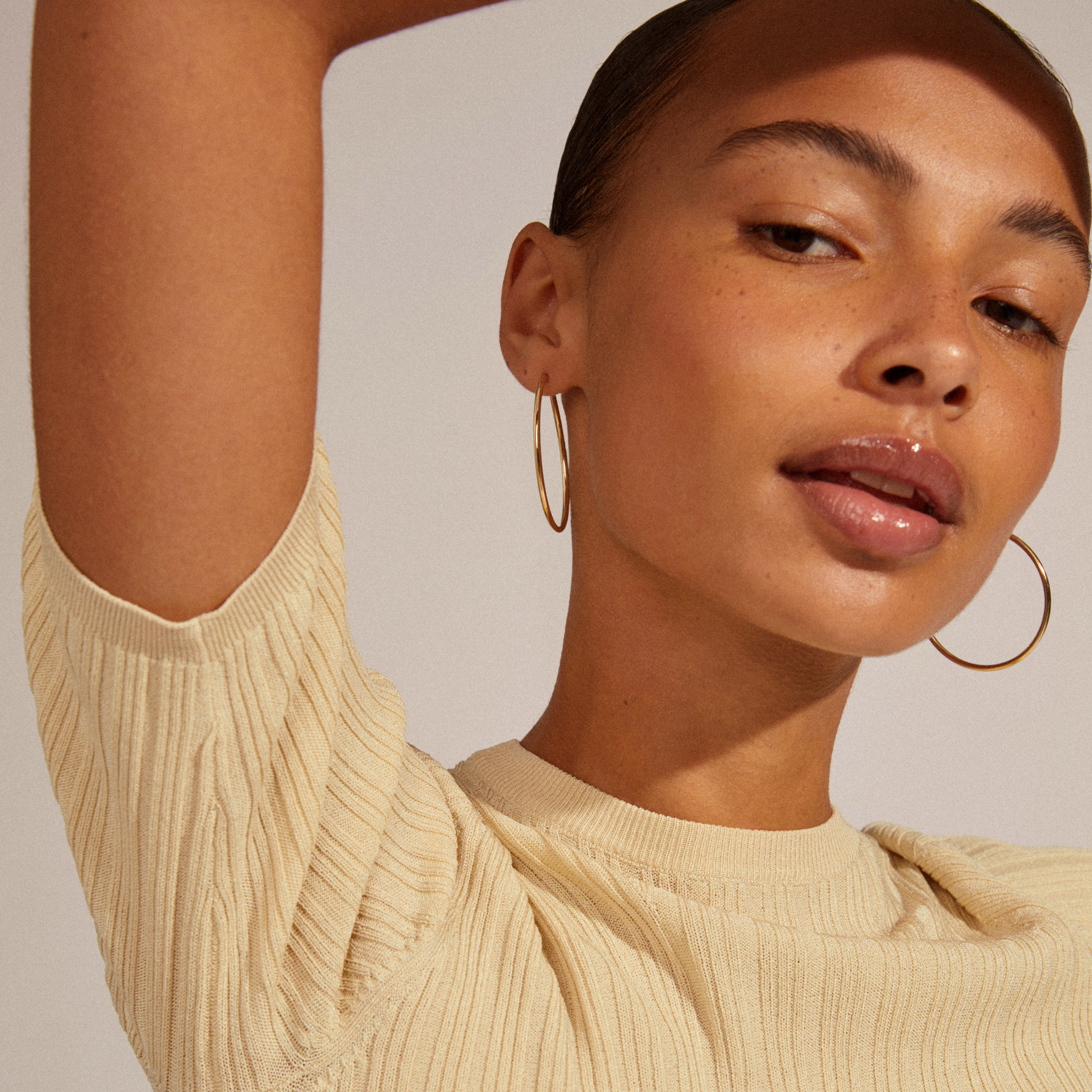 APRIL medium-size gold-plated hoop earrings, 40 mm, worn by a woman. These classic, recycled hoops complement any outfit.