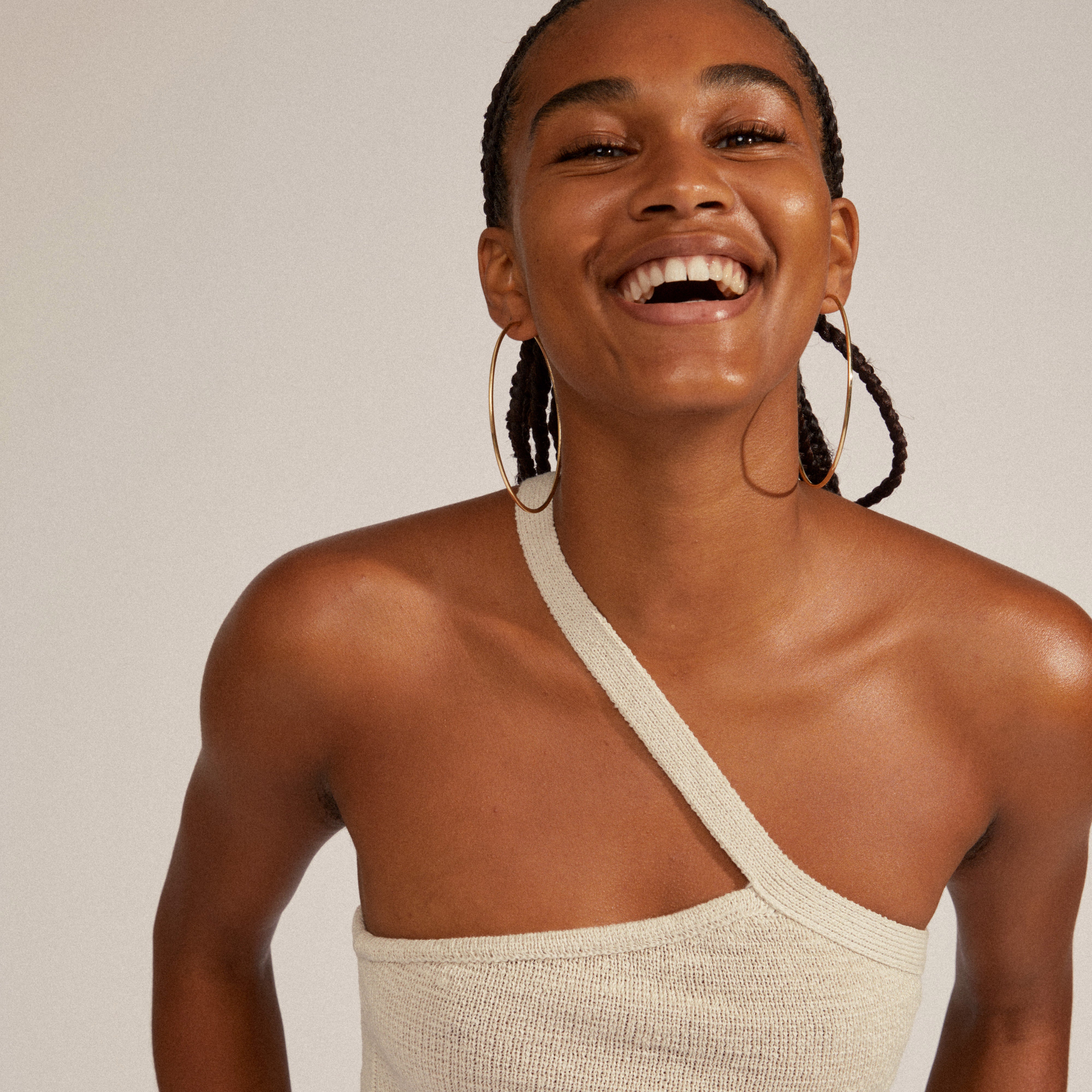 APRIL maxi hoop earrings gold-plated, worn by a smiling person, showcasing their elegant, 80 mm diameter and timeless, slim silhouette design.