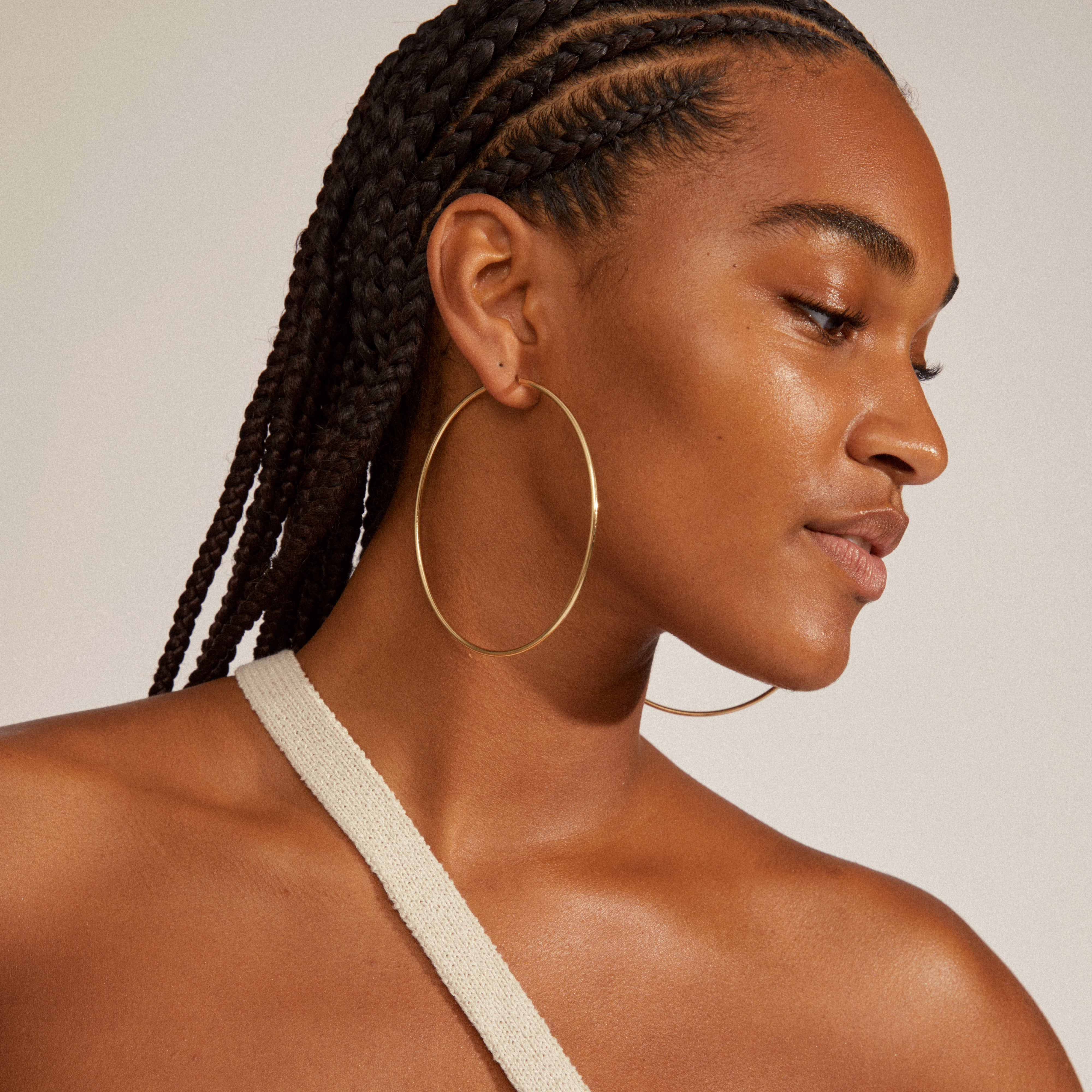 APRIL maxi hoop earrings gold-plated adorn a person with dreadlocks, showcasing their elegant, slim design and bold 80 mm diameter for a stylish, standout look.