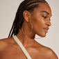 APRIL maxi hoop earrings gold-plated adorn a person with dreadlocks, showcasing their elegant, slim design and bold 80 mm diameter for a stylish, standout look.