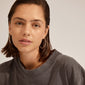 A woman wearing APRIL medium-size hoop earrings, silver-plated, showcasing their elegance and versatility in a close-up portrait.