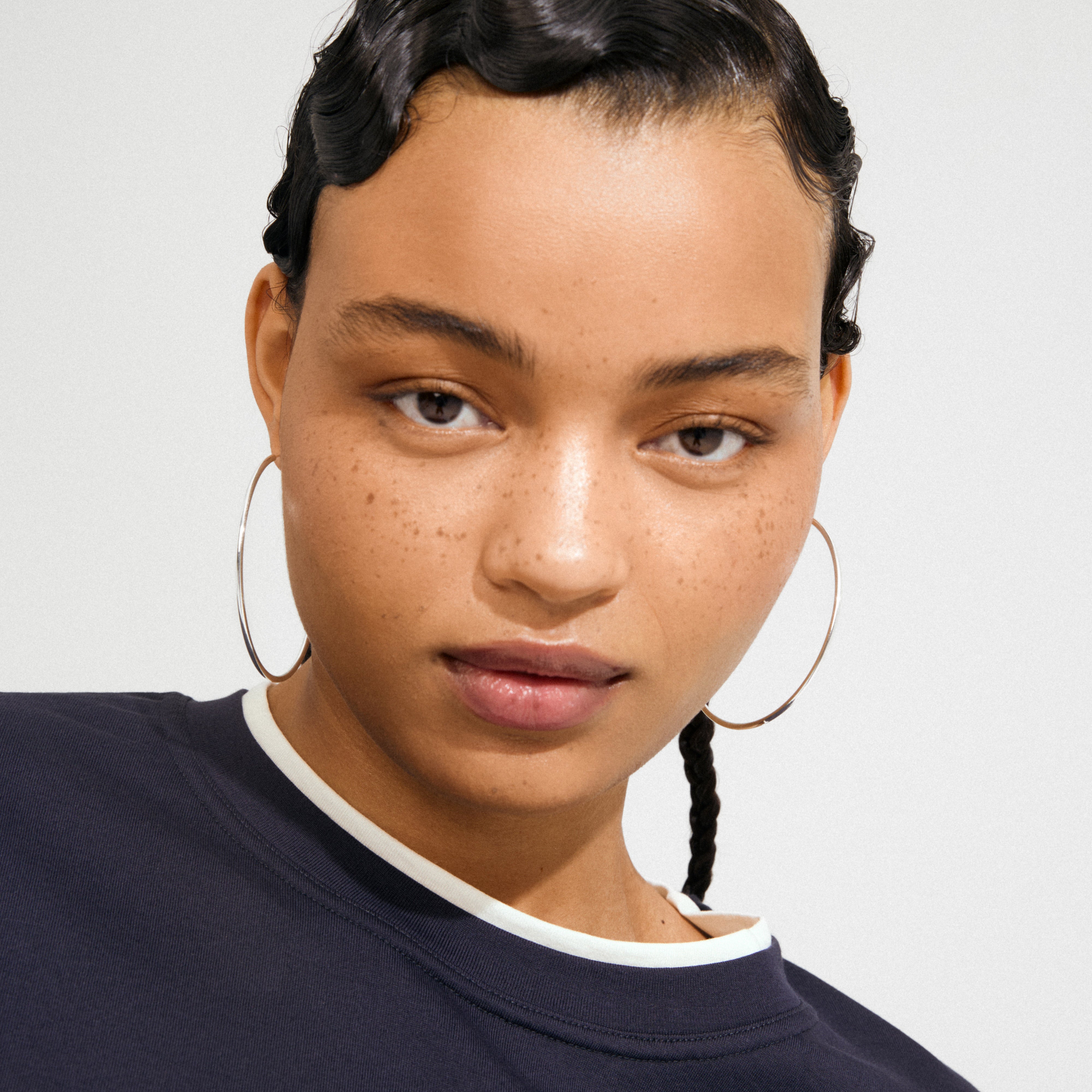 Young woman wearing APRIL large hoop earrings, silver-plated, showcasing their elegant 60 mm diameter design, perfect for elevating any outfit with classic Danish flair.