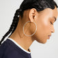 Side profile showcasing APRIL large silver-plated hoop earring, 60 mm diameter, highlighting elegant design with recycled material, worn by a young woman with braided hair.