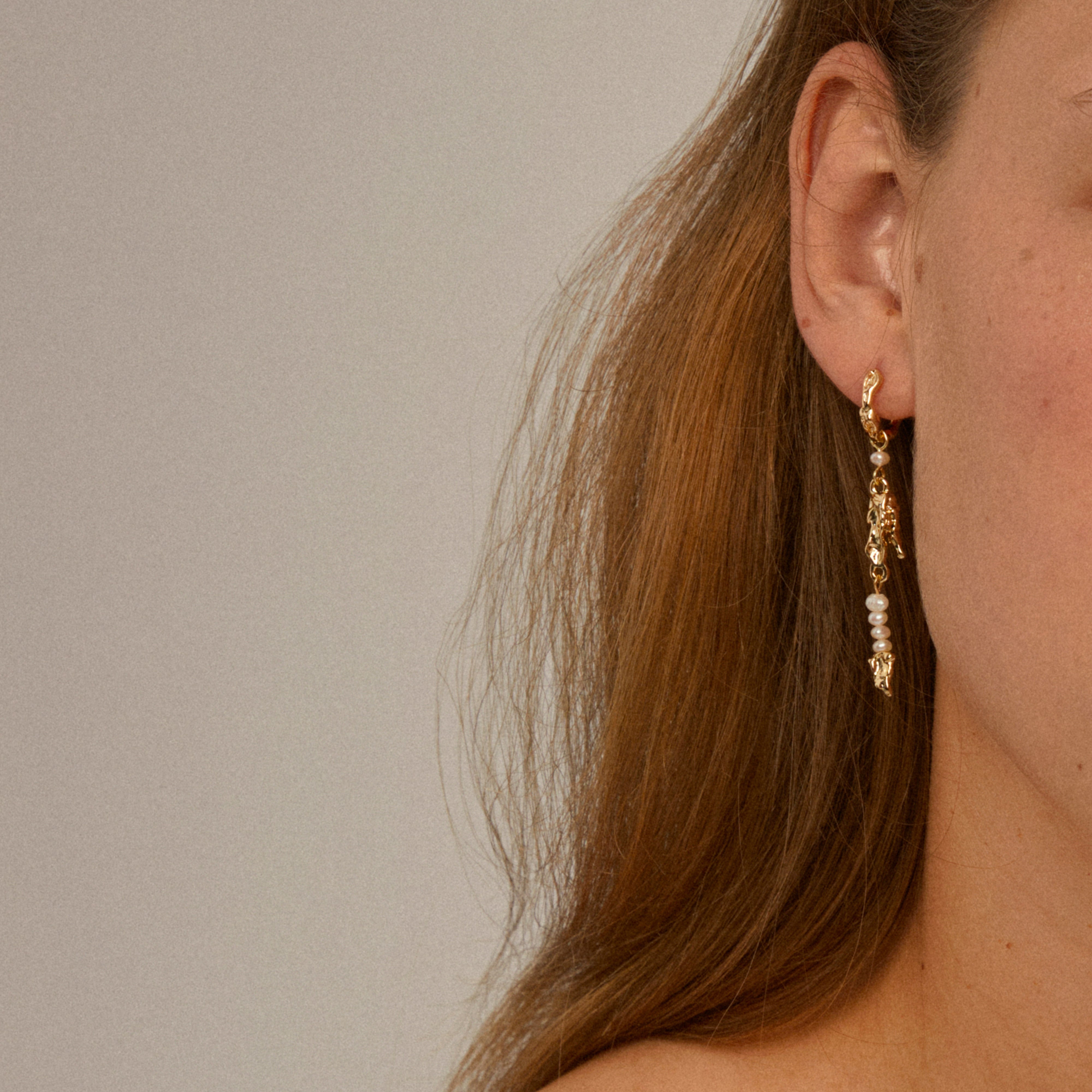 Close-up of NIYA freshwater pearl earrings, showcasing organic gold-plated links and delicate pearls, capturing Pilgrim's blend of timeless elegance and playful summer style.