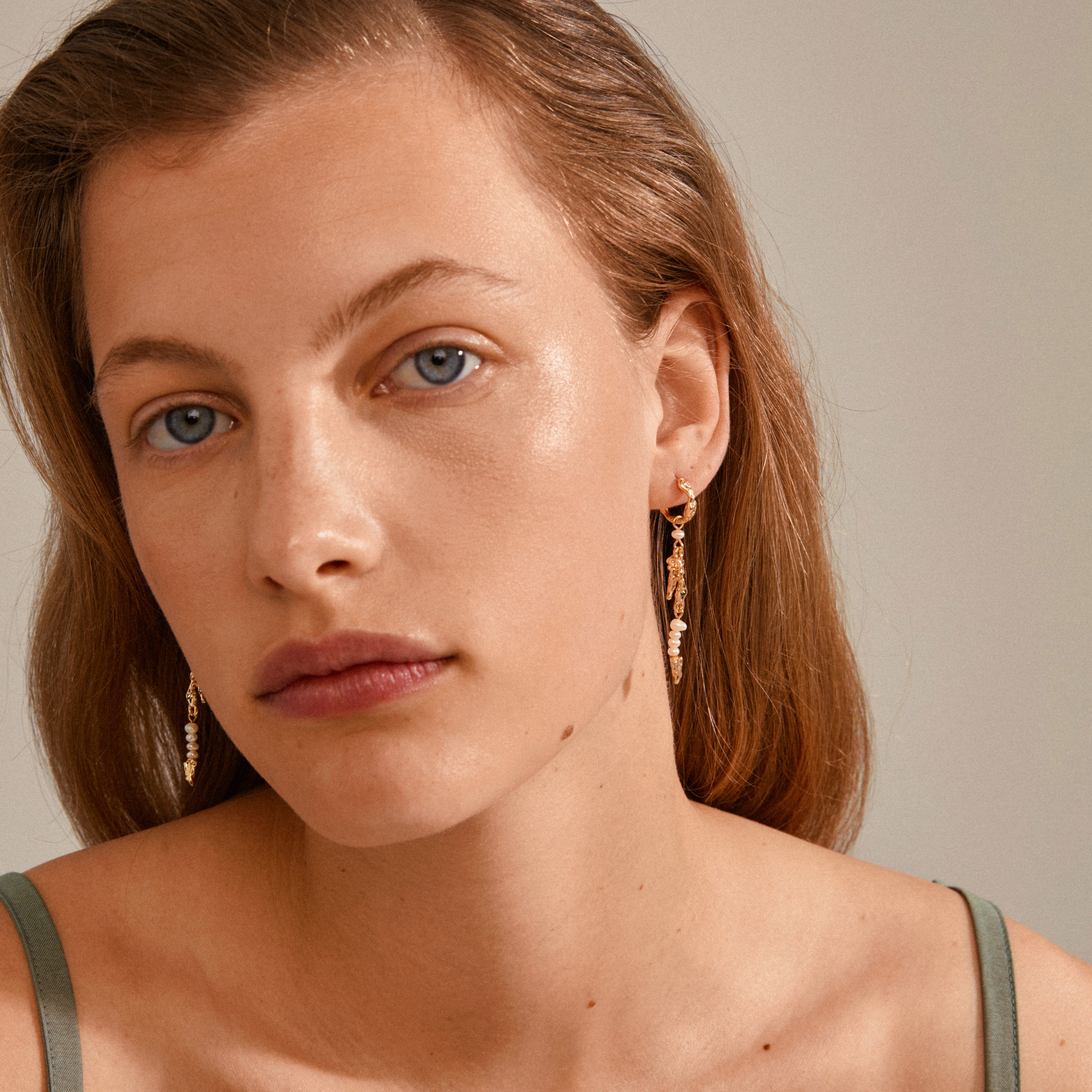 NIYA freshwater pearl earrings, gold-plated, featuring organic shapes, adorn a woman with long hair, highlighting their playful elegance for summer styling.
