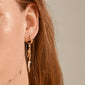 Close-up of NIYA freshwater pearl earrings by Pilgrim; featuring gold-plated hoops with decorative links and pearls, highlighting trendy, handmade Danish design.