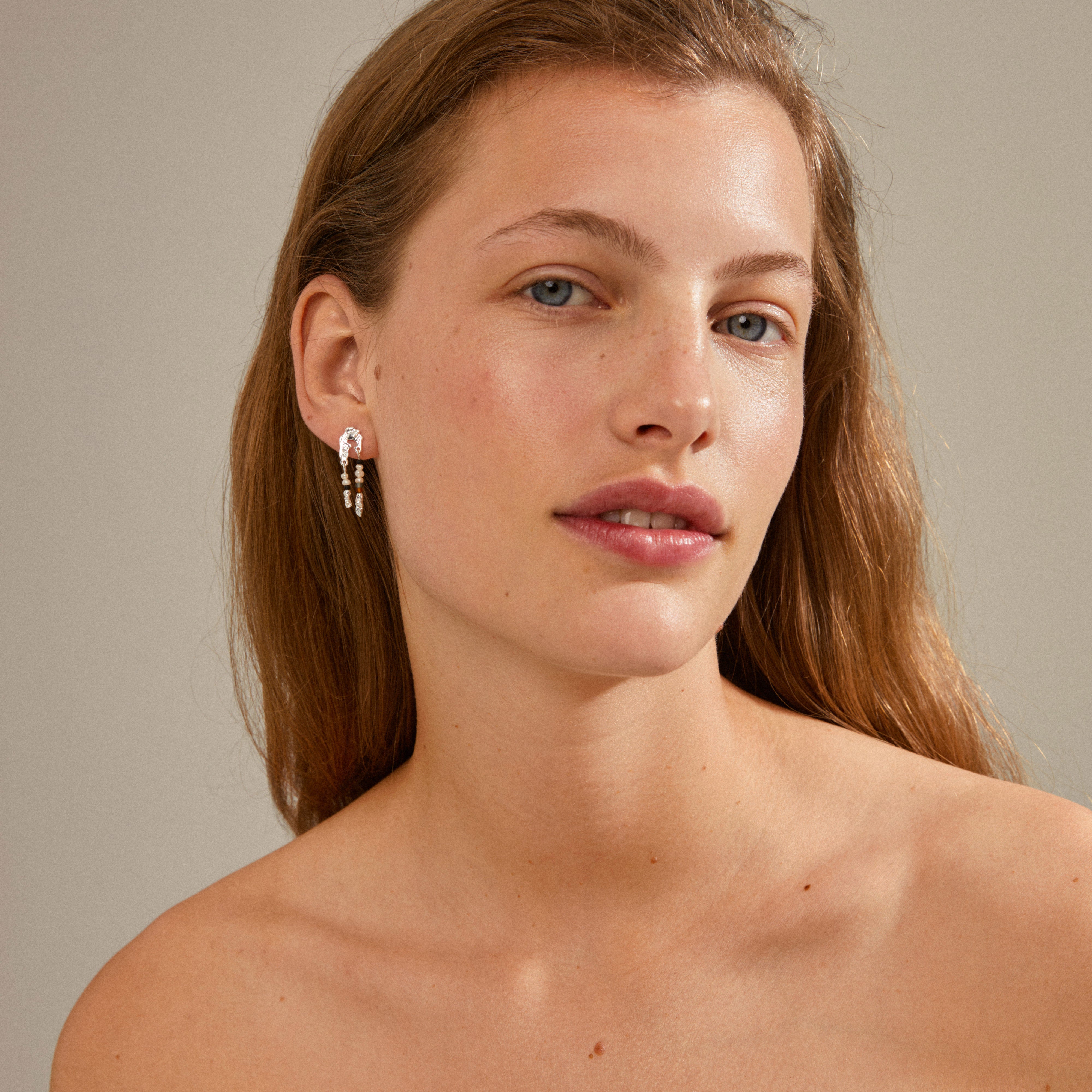 NIYA earrings on a woman's ear, showcasing their multi-colored, silver-plated design. Perfect for enhancing summer looks with a handcrafted, trendy feel.