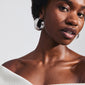 Close-up of a woman wearing large, silver-plated ELENI earrings by Pilgrim, showcasing their rustic, perforated design and bold, wide silhouette.
