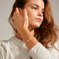 Woman showcasing the INDIANA bracelet, featuring freshwater pearls, grey agate, and faceted beads, elegantly draped on her wrist for a stylish, layered look.