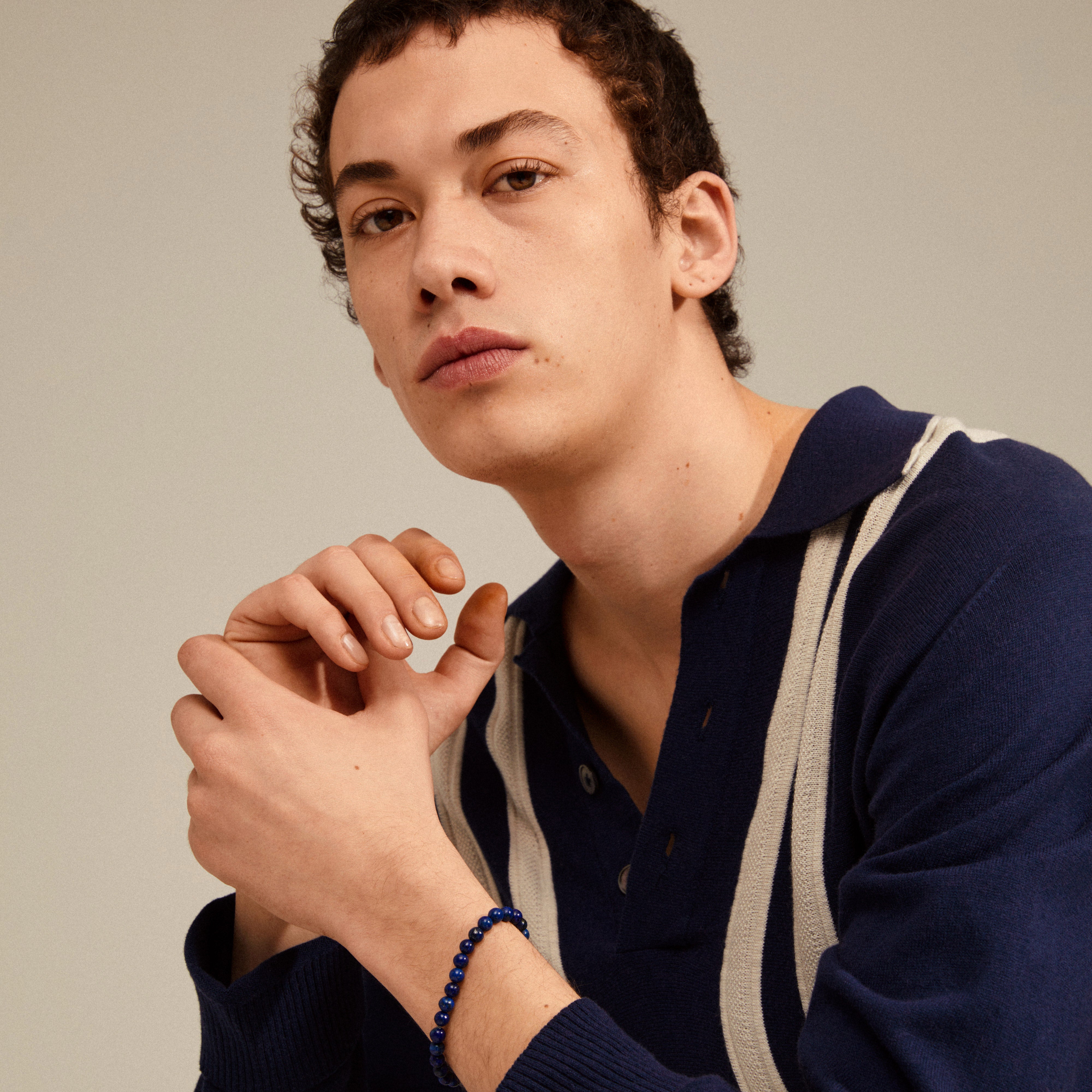 POWERSTONE bracelet with genuine lapis lazuli stones, featuring round forms on a durable elastic band, worn by a man posing, highlighting its elegant and spiritual appeal.