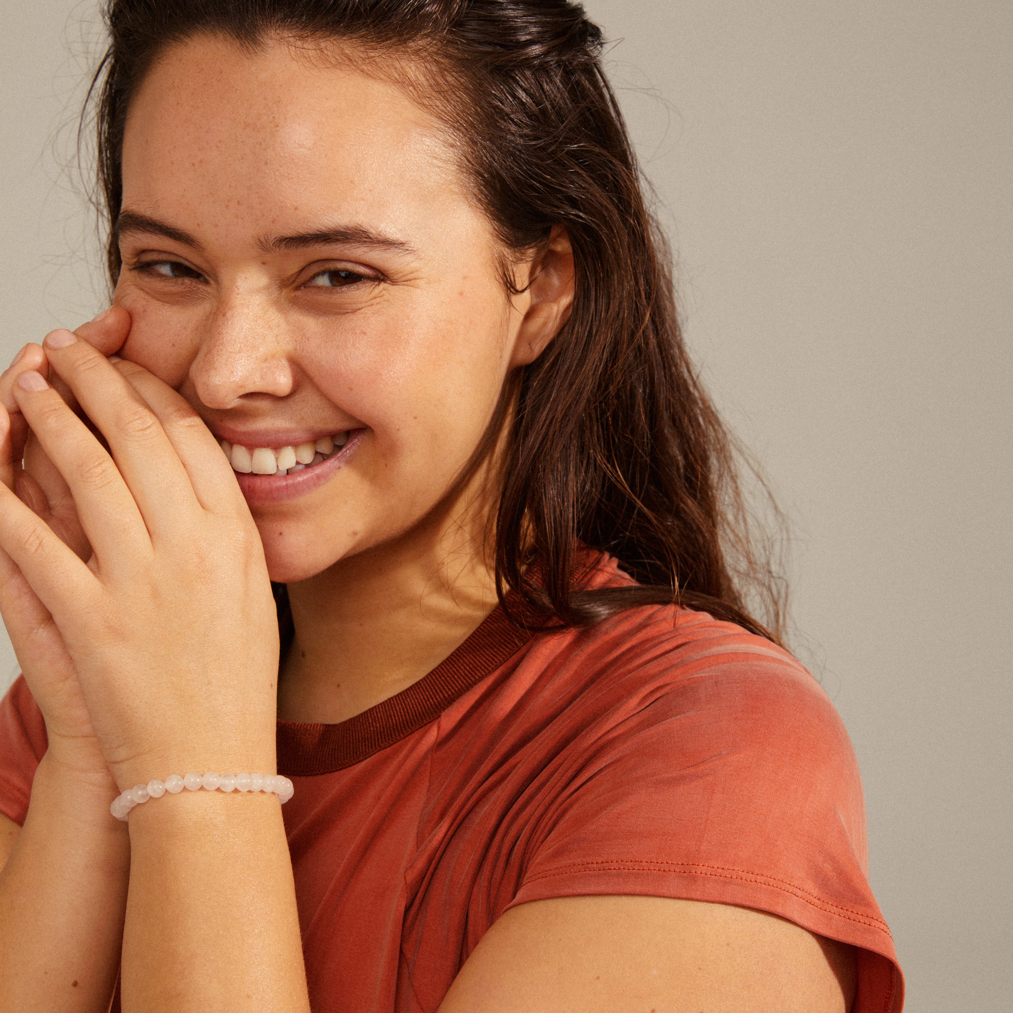 Woman wearing the POWERSTONE bracelet with round rose quartz beads, showcasing its elegant design and harmonious energy on her wrist.