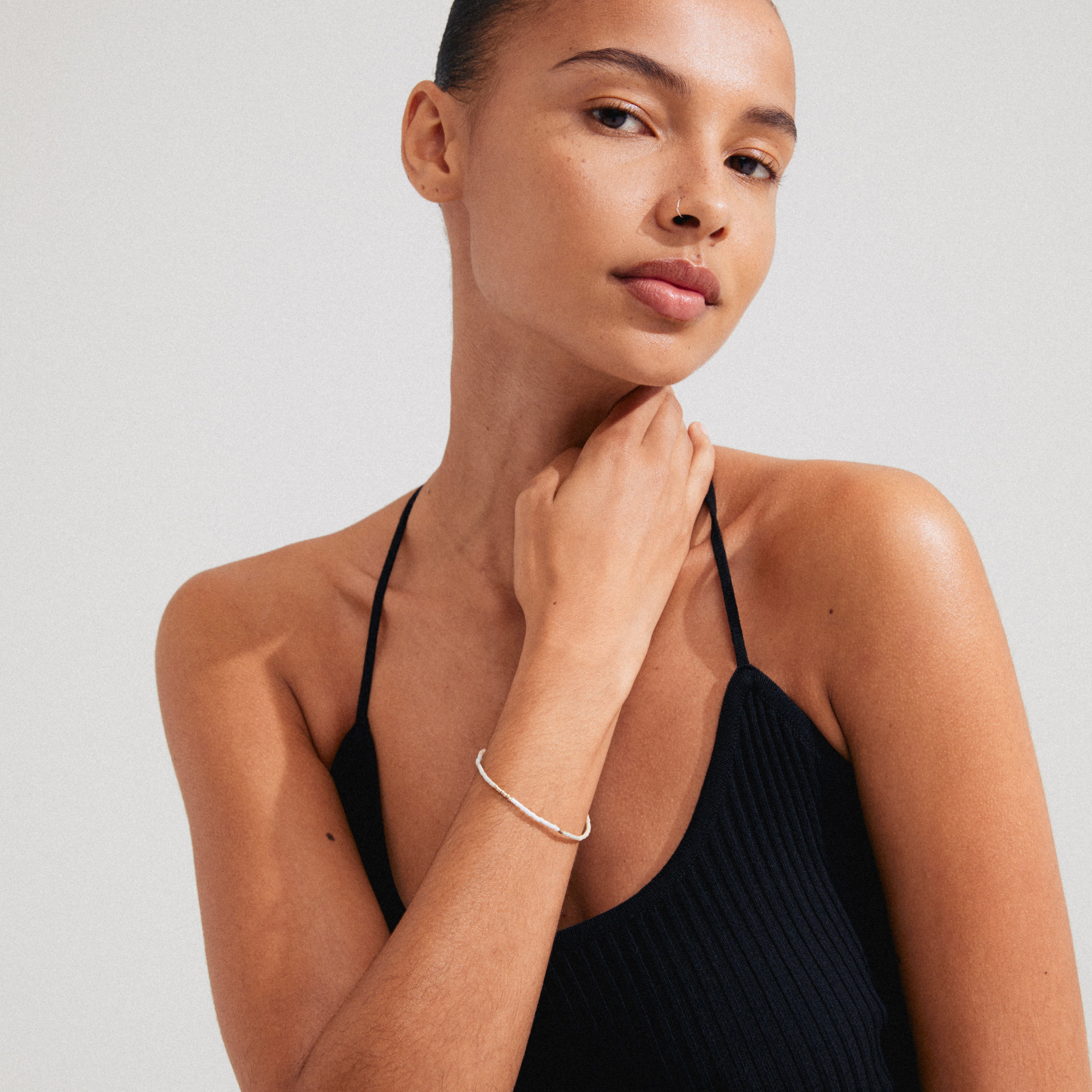 Woman wearing the Pilgrim ALISON bracelet, featuring white and grey glass beads on a lycra elastic band, perfect for stacking with other bracelets.