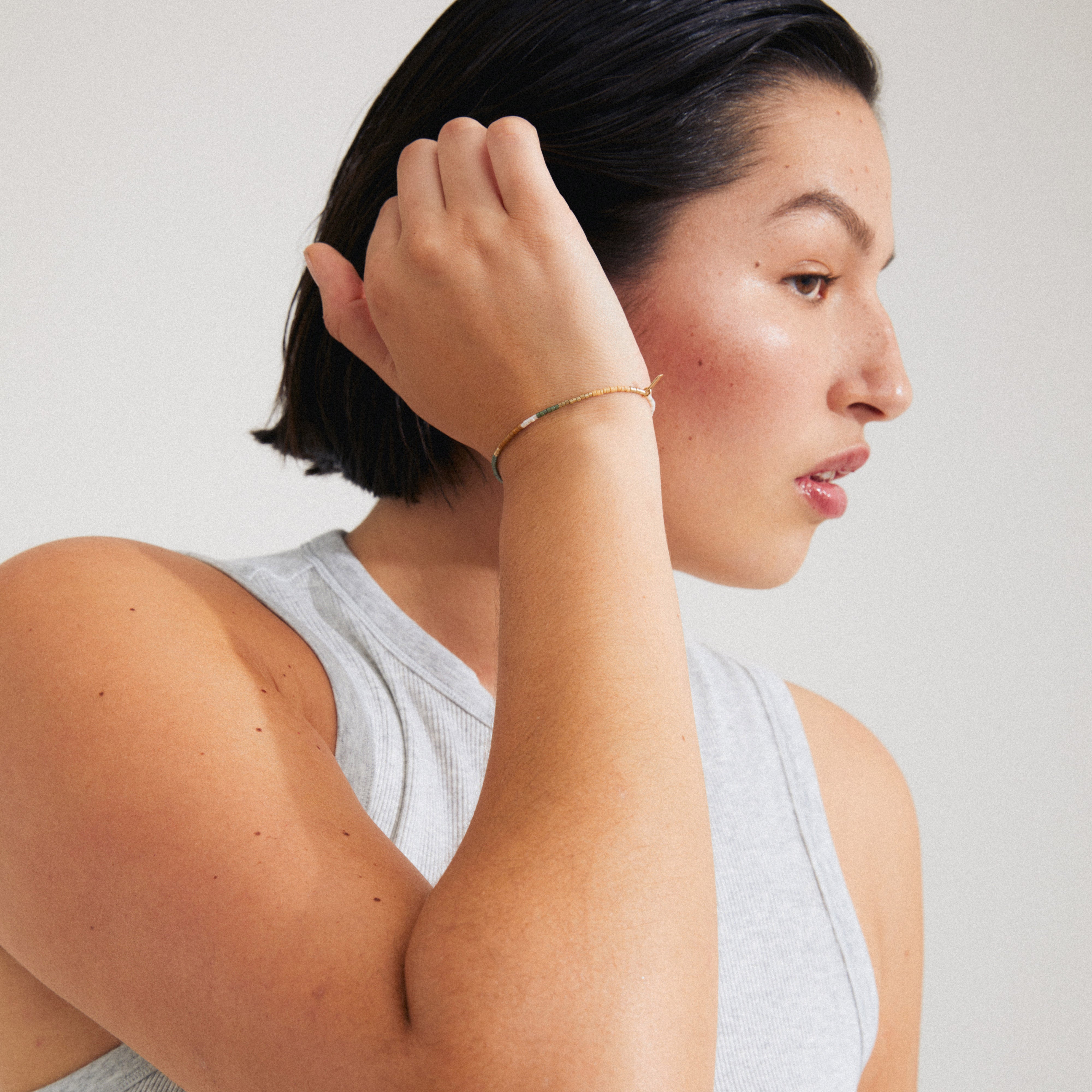 Woman wearing Pilgrim's ALISON bracelet, showcasing taupe and grey glass beads, embodying a boho-inspired style for stacking and personalization.