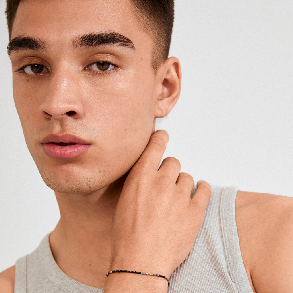 Young man wearing the ALISON bracelet in black and gold, showcasing its sleek design and boho vibes on his right wrist.