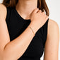 Person wearing a sleeveless black top showcases the ALISON bracelet by Pilgrim, featuring thin, multi-colored beads on a stretchy band, embodying boho festival style.