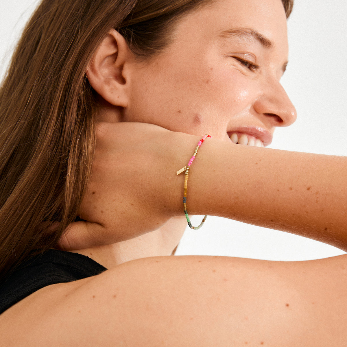 Young woman wearing the ALISON bracelet, a slim, multicolored beaded accessory, highlighting her casual, boho style with a subtle, vibrant touch.