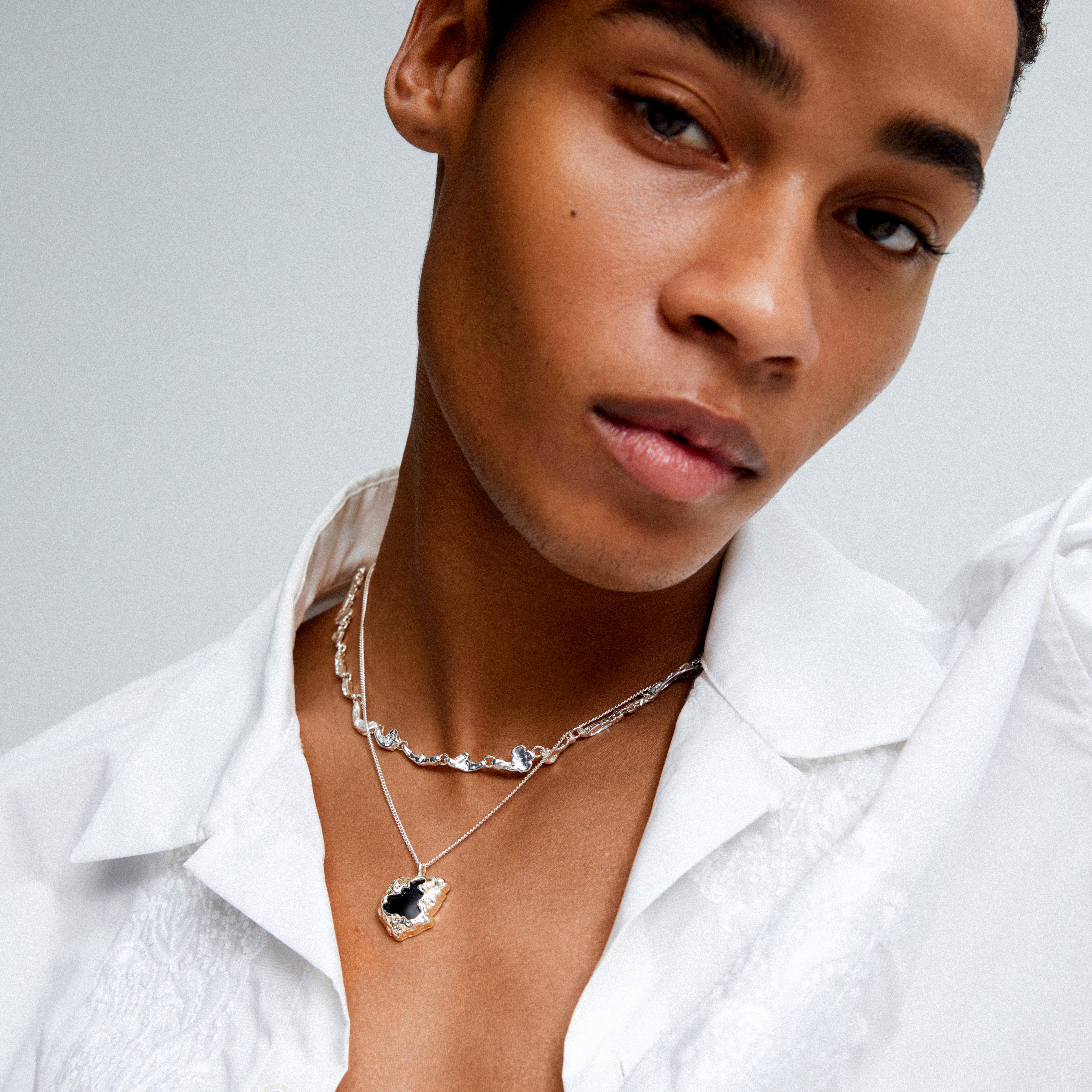 FRANK pendant necklace silver-plated featuring black agate stone in organic silver setting, worn by a person, showcasing its unique and customizable design.