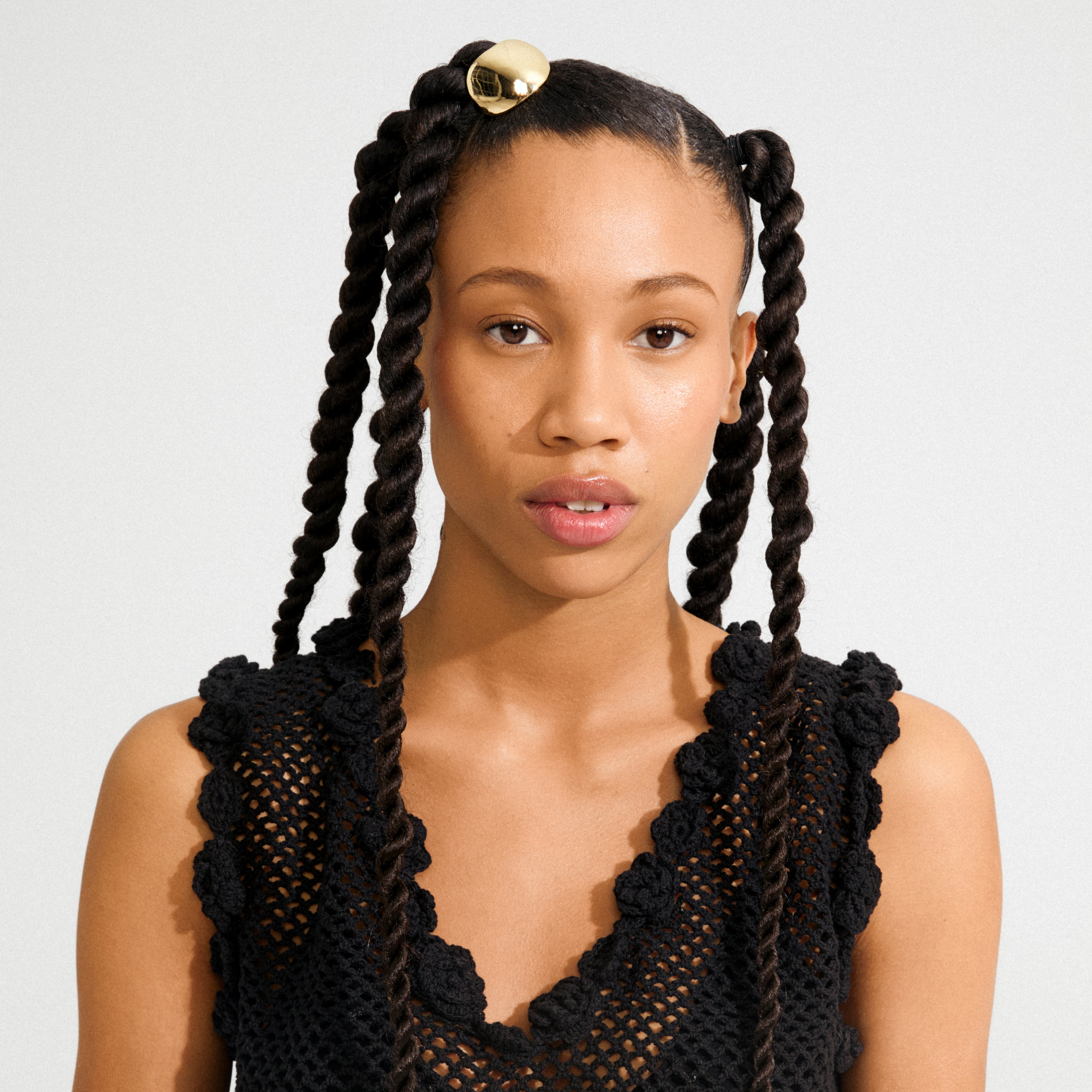 Young woman wearing the AMARIS hair accessory, a sleek gold-plated clip, adds elegance to her two-strand twist pigtails. Perfect for elevating everyday hairstyles.