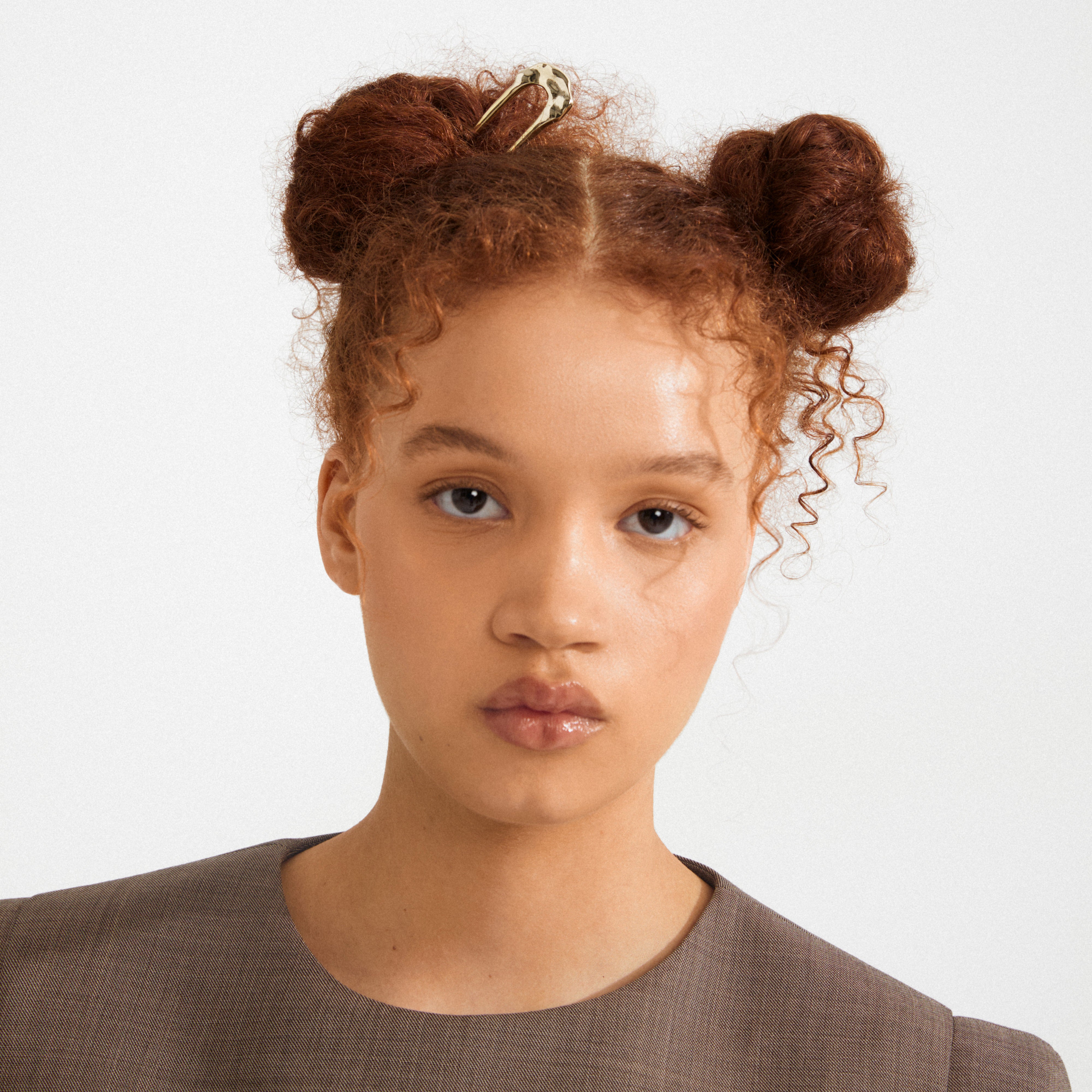 Young person with two buns styled using the AMARIS hairpin, showcasing its sleek, gold-plated design for effortless elegance and everyday versatility.