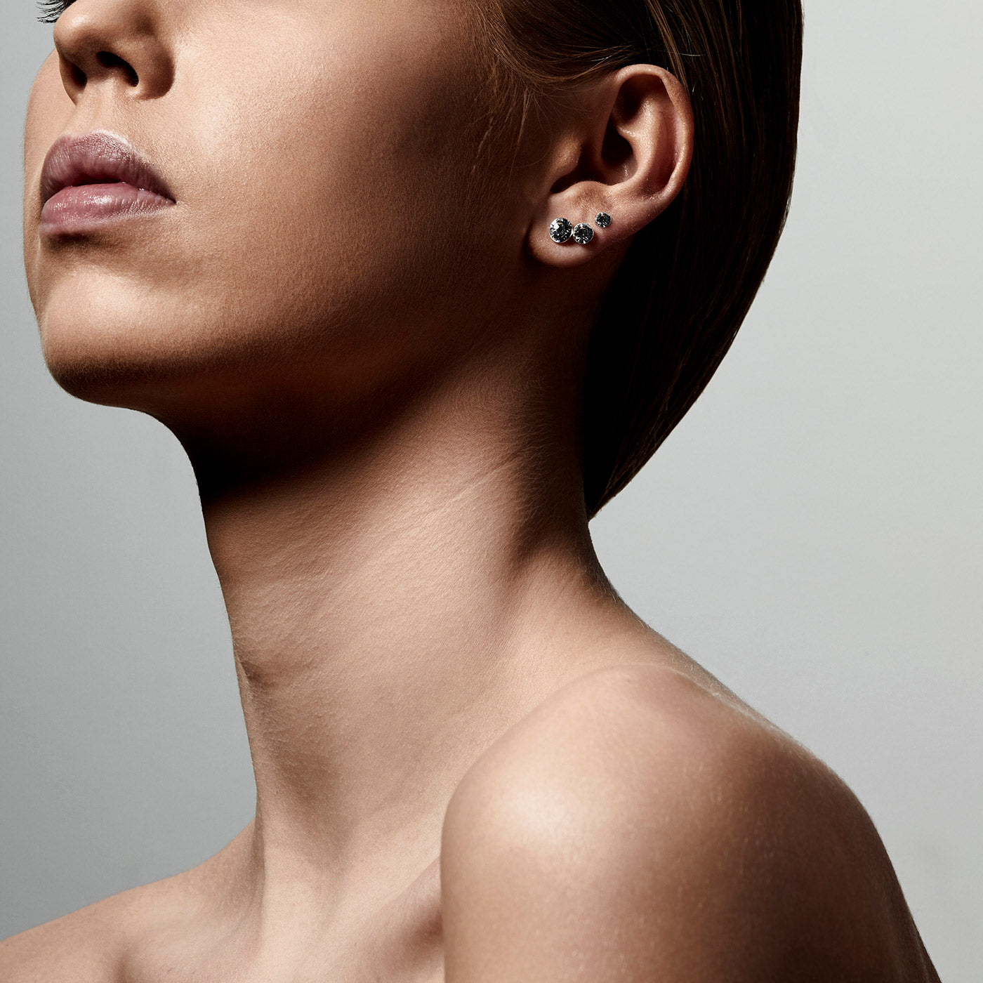 Close-up of a woman's ear adorned with the MILLIE 3-in-1 set of silver-plated crystal studs, showcasing versatile, elegant earring options.
