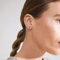 Close-up of a woman's ear wearing the gold-plated PHYLLIS single earring, shaped like the tree of life, symbolizing growth and connection.