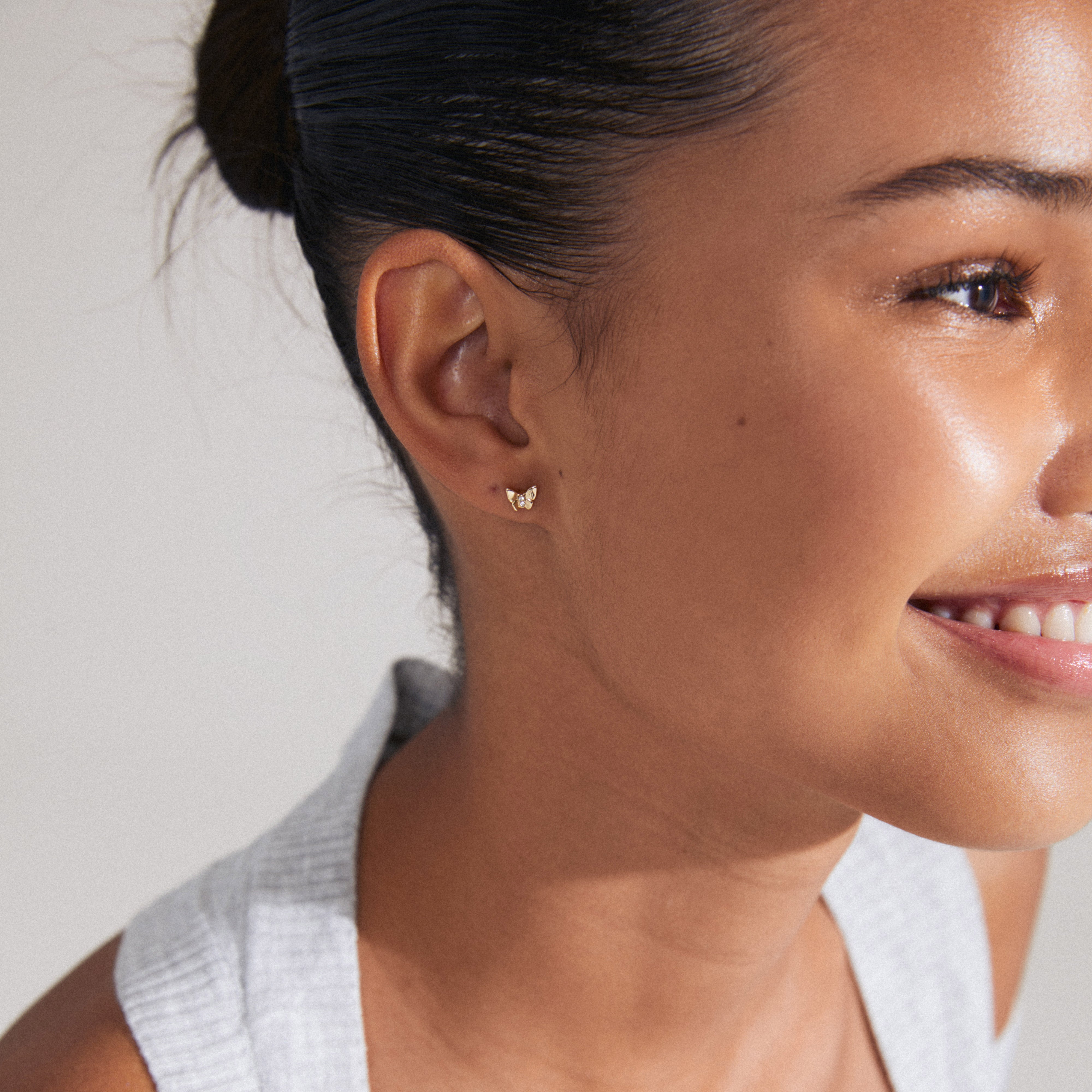 OLYMPIA single earring, gold-plated butterfly design with Preciosa crystals, worn by a woman with hair pulled back, showcasing subtle sparkle and elegance.