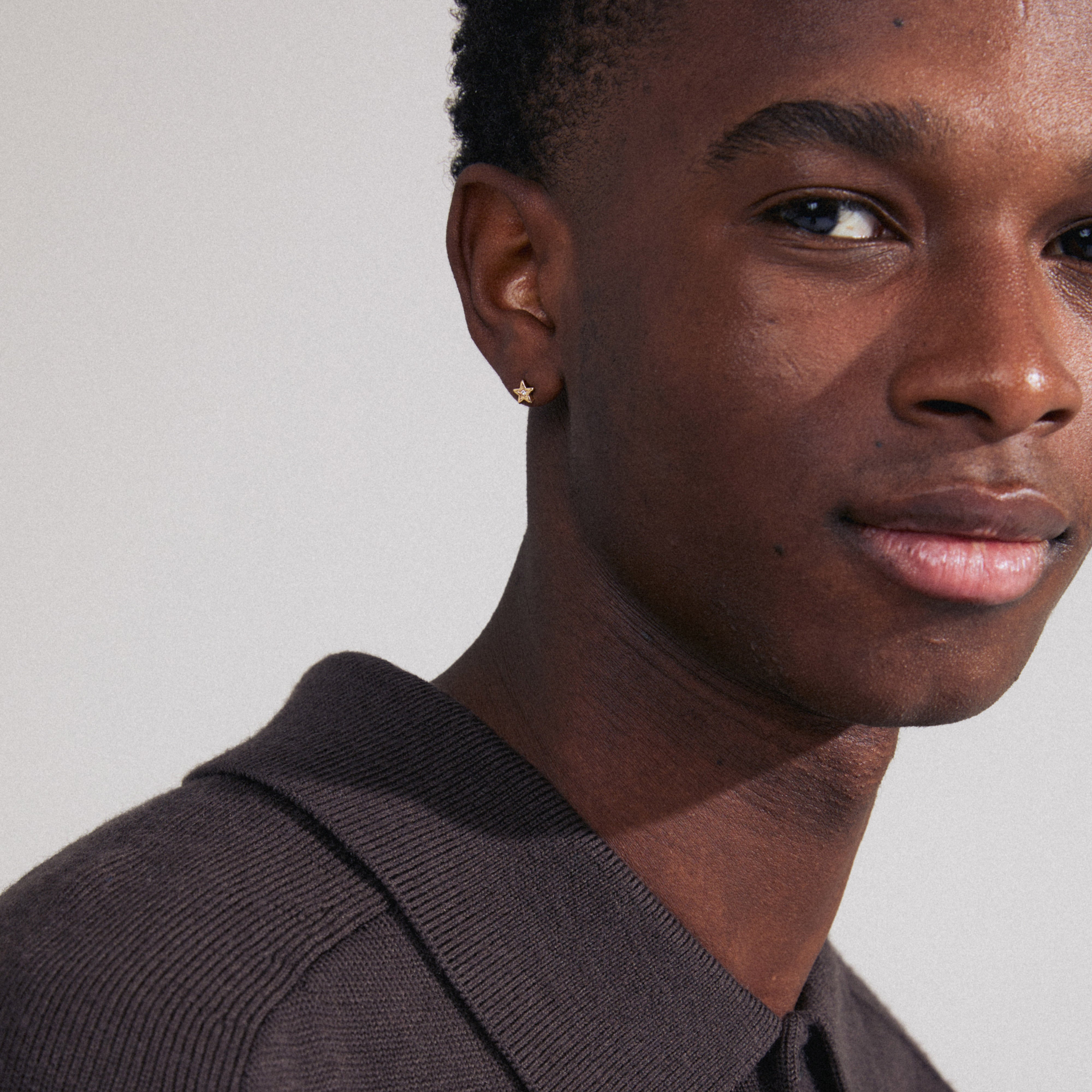 Close-up of a man wearing the NYX single earring, gold-plated with a sparkling Preciosa crystal, capturing the light beautifully.