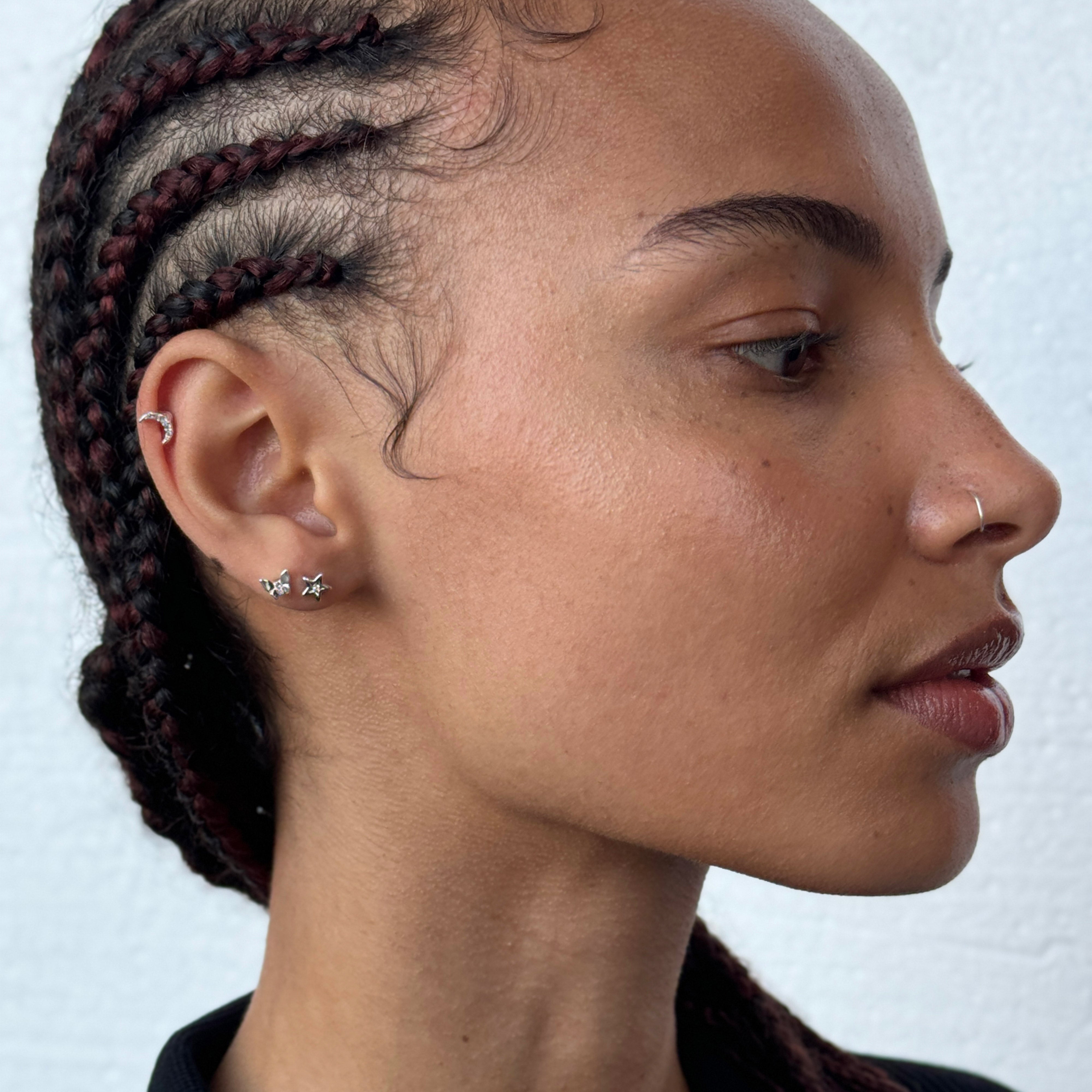 Close-up of a woman's ear wearing the NYX single silver-plated earring by Pilgrim, adorned with a sparkling Preciosa crystal.
