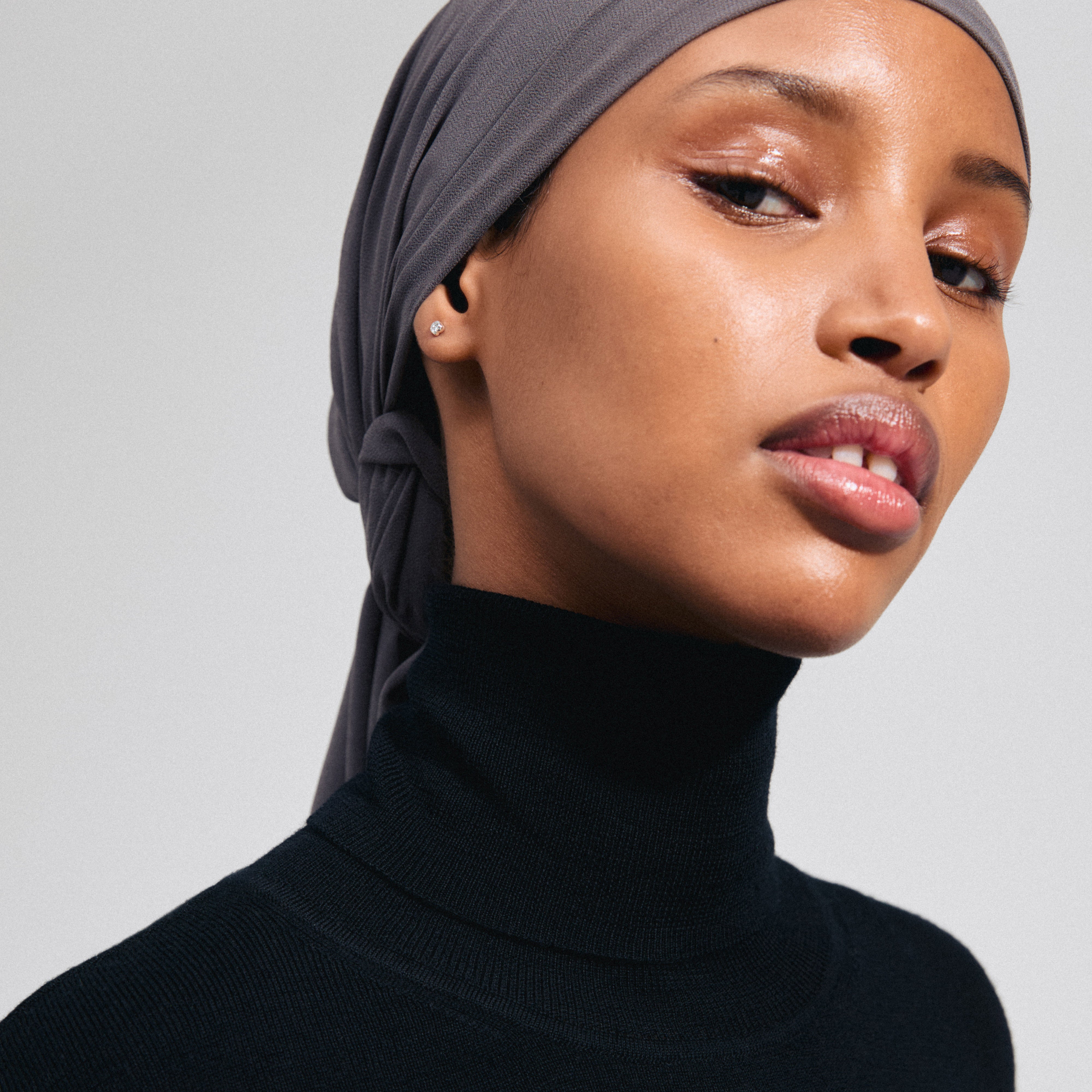 PELAGIA single earring, silver-plated, displayed on a woman wearing a headscarf. The earring's unique organic shape and rustic surface catch the light elegantly.