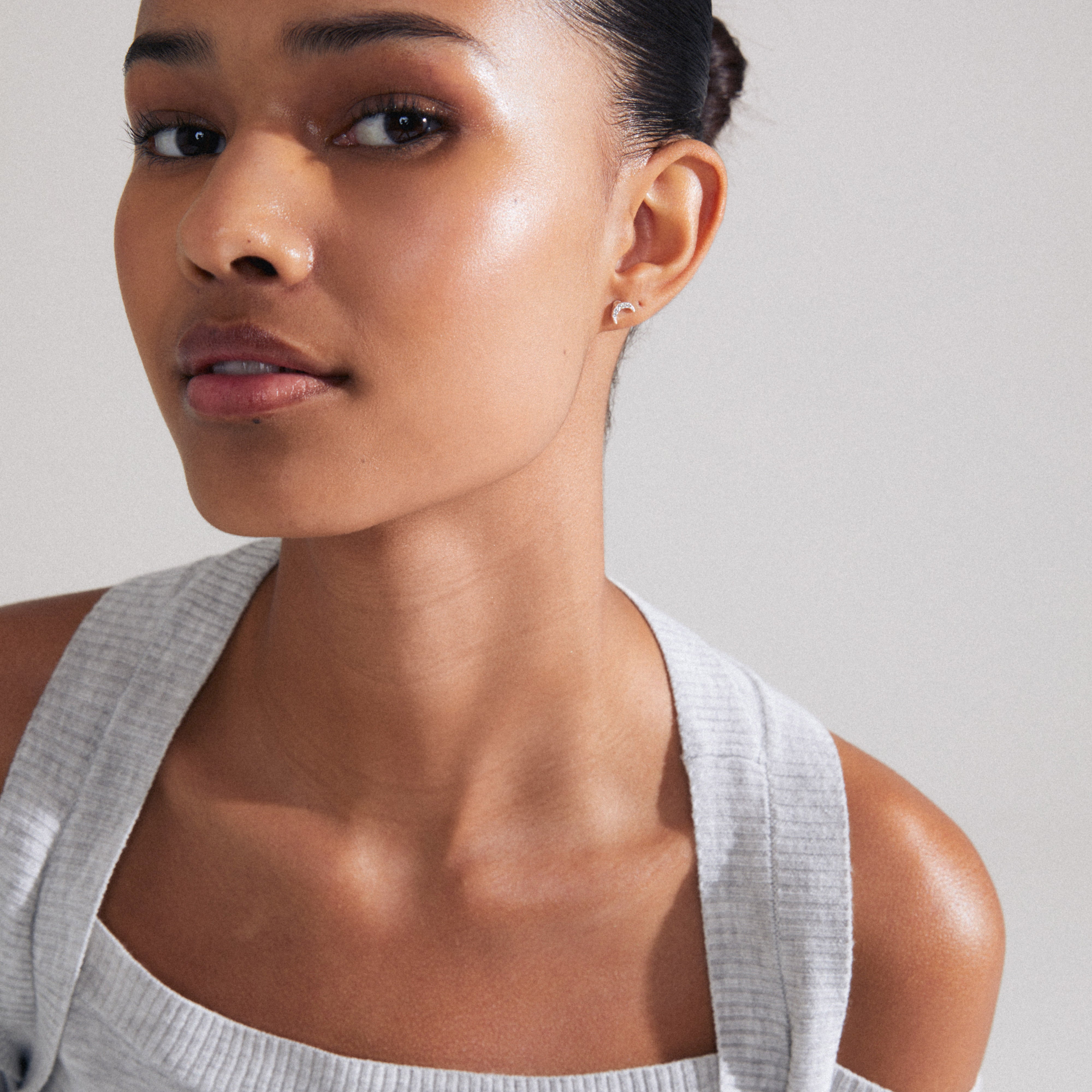 MELINA single earring, silver-plated, features a crescent moon shape with Preciosa crystals, capturing elegance and celestial charm. Modeled by a woman with a ponytail.