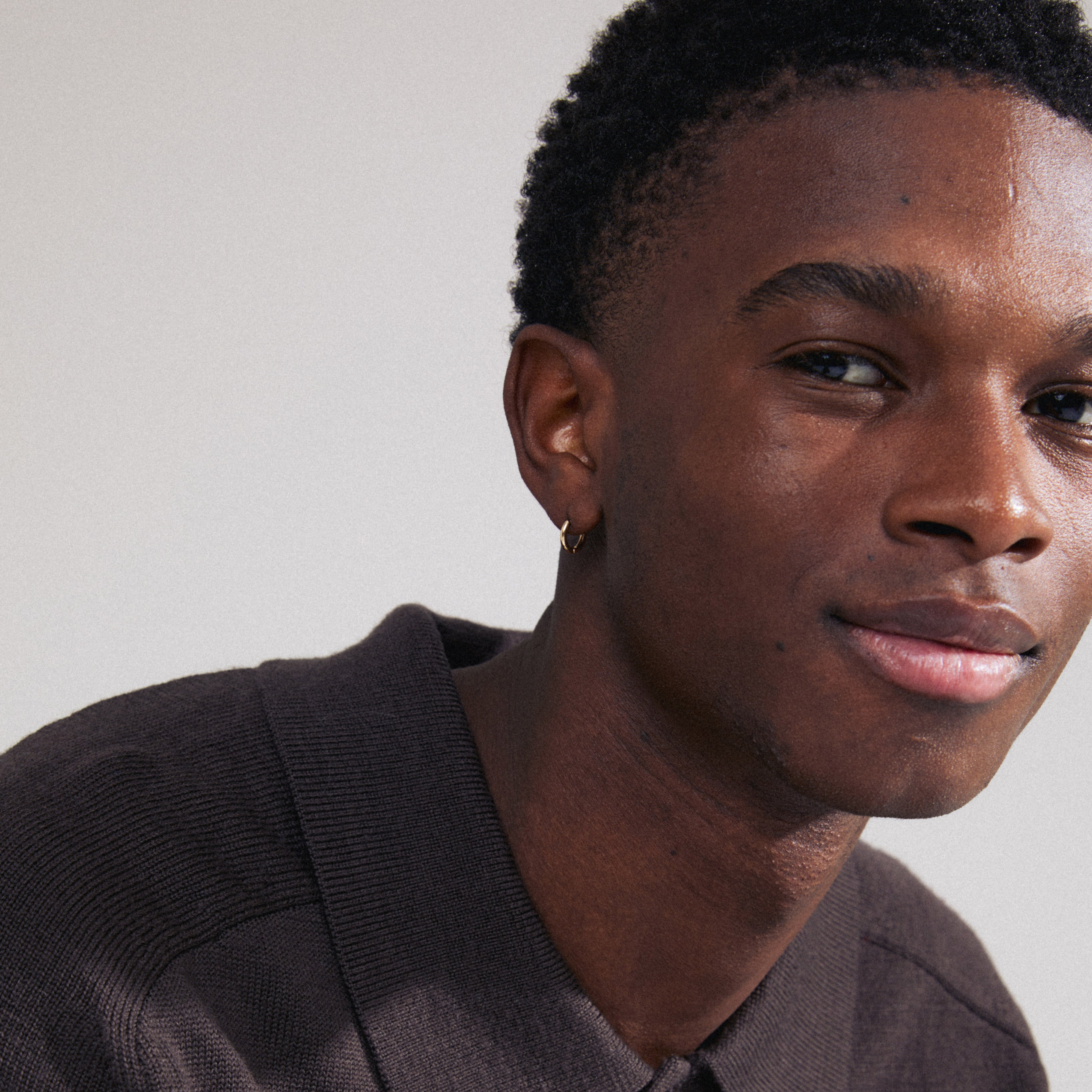 LAVRA single earring gold-plated displayed as part of a stylish, close-up portrait of a man, highlighting the earring's shiny finish and timeless design.