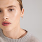 KYRA single earring gold-plated with an organic shape and shiny finish, worn by a woman in a grey sweater, showcasing its handcrafted elegance.