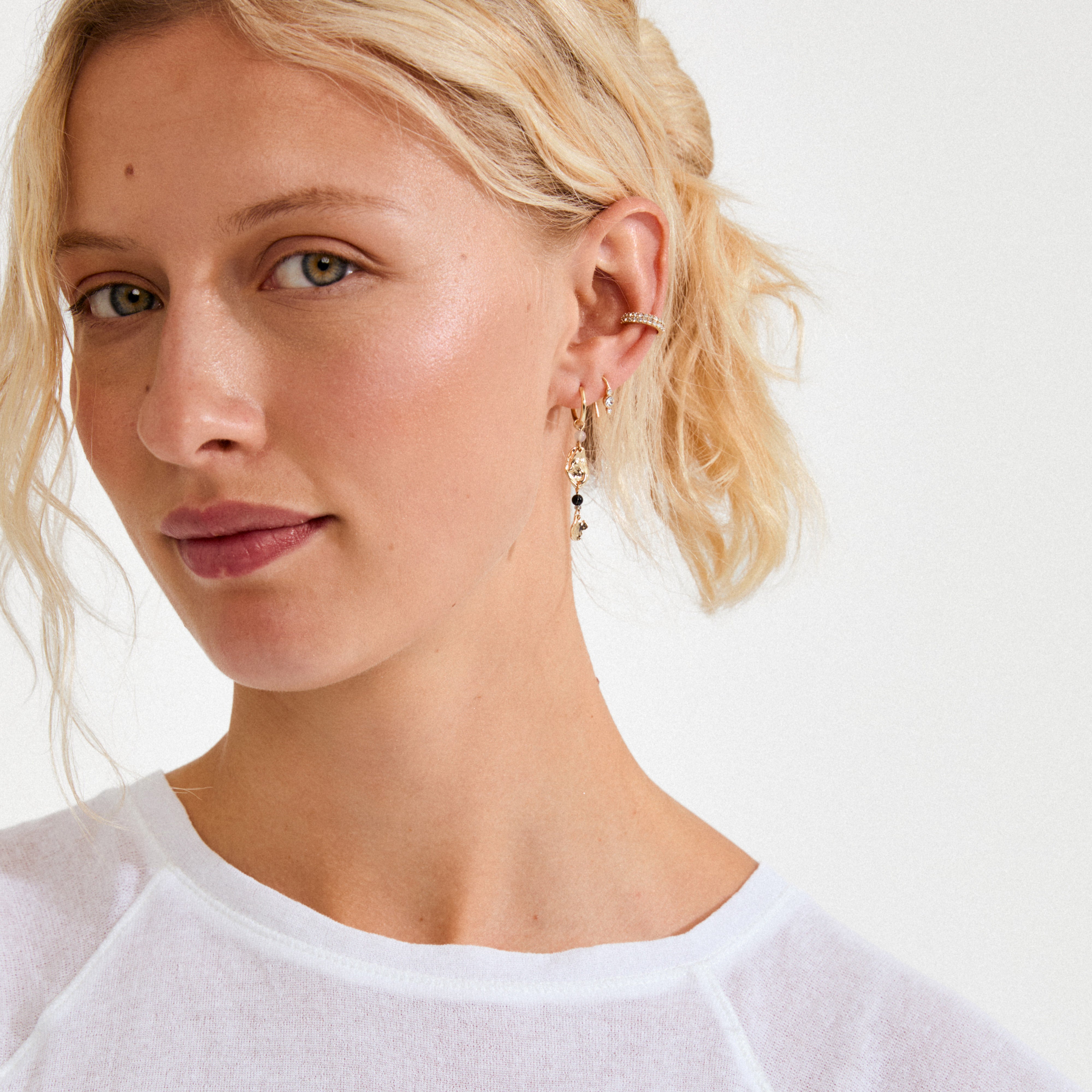 Young woman wearing the KRISTINE single earring, gold-plated with a dangling pendant of three sparkling Preciosa crystals, highlighting a trendy and elegant style.