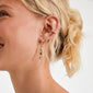 Profile of a woman wearing the KRISTINE single gold-plated earring with a textured nugget and black bead, styled with two additional gold earrings.