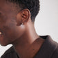 LAVRA single earring silver-plated, worn by a smiling man, showcasing its shiny finish and timeless huggie hoop design.