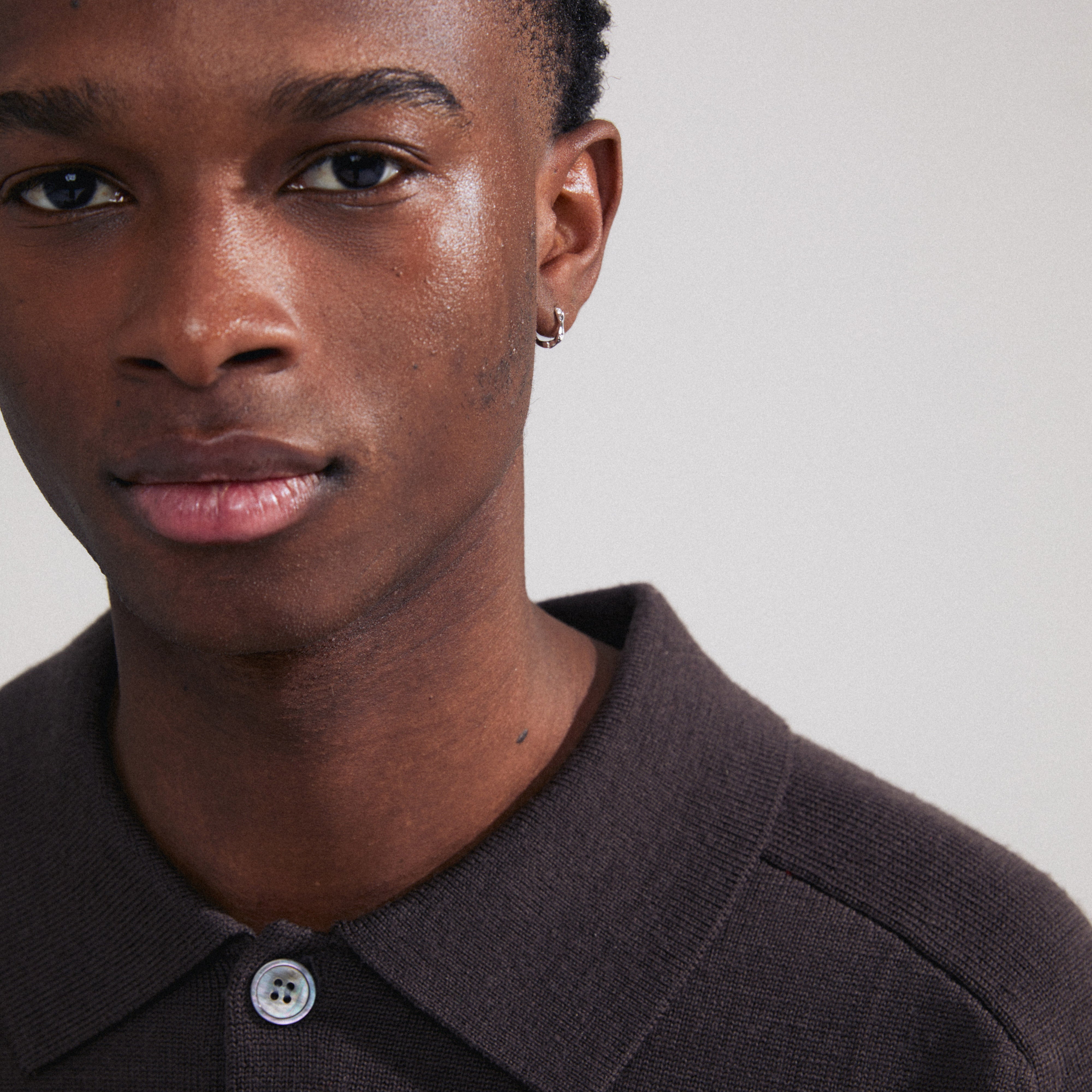 KYRA single earring silver-plated, worn by a man in a brown shirt, showcases its shiny, handcrafted design and easy click clasp for effortless elegance.
