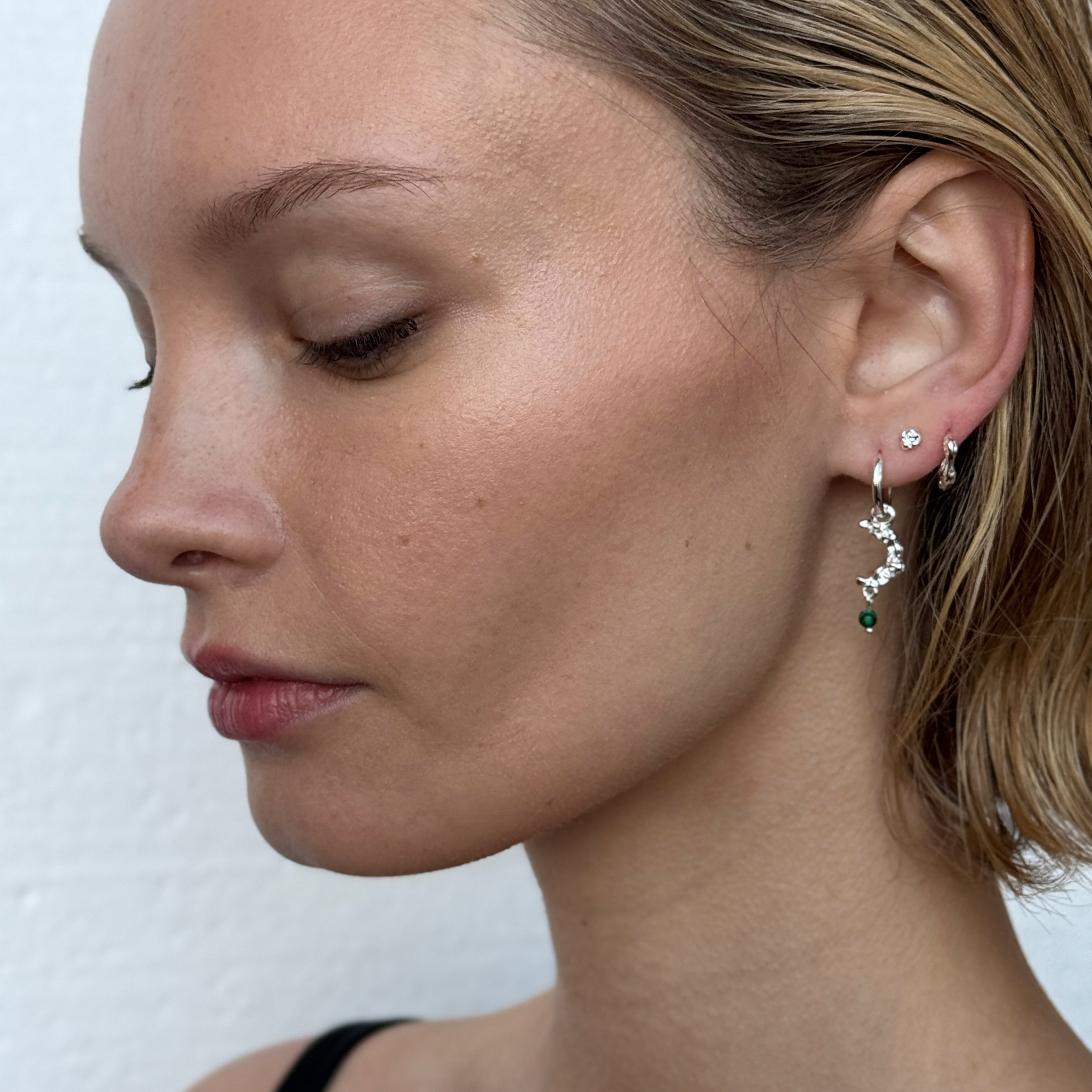 KYRA single earring silver-plated, featuring a shiny, organic shape and handcrafted vibe, worn by a woman with blonde hair and closed eyes.