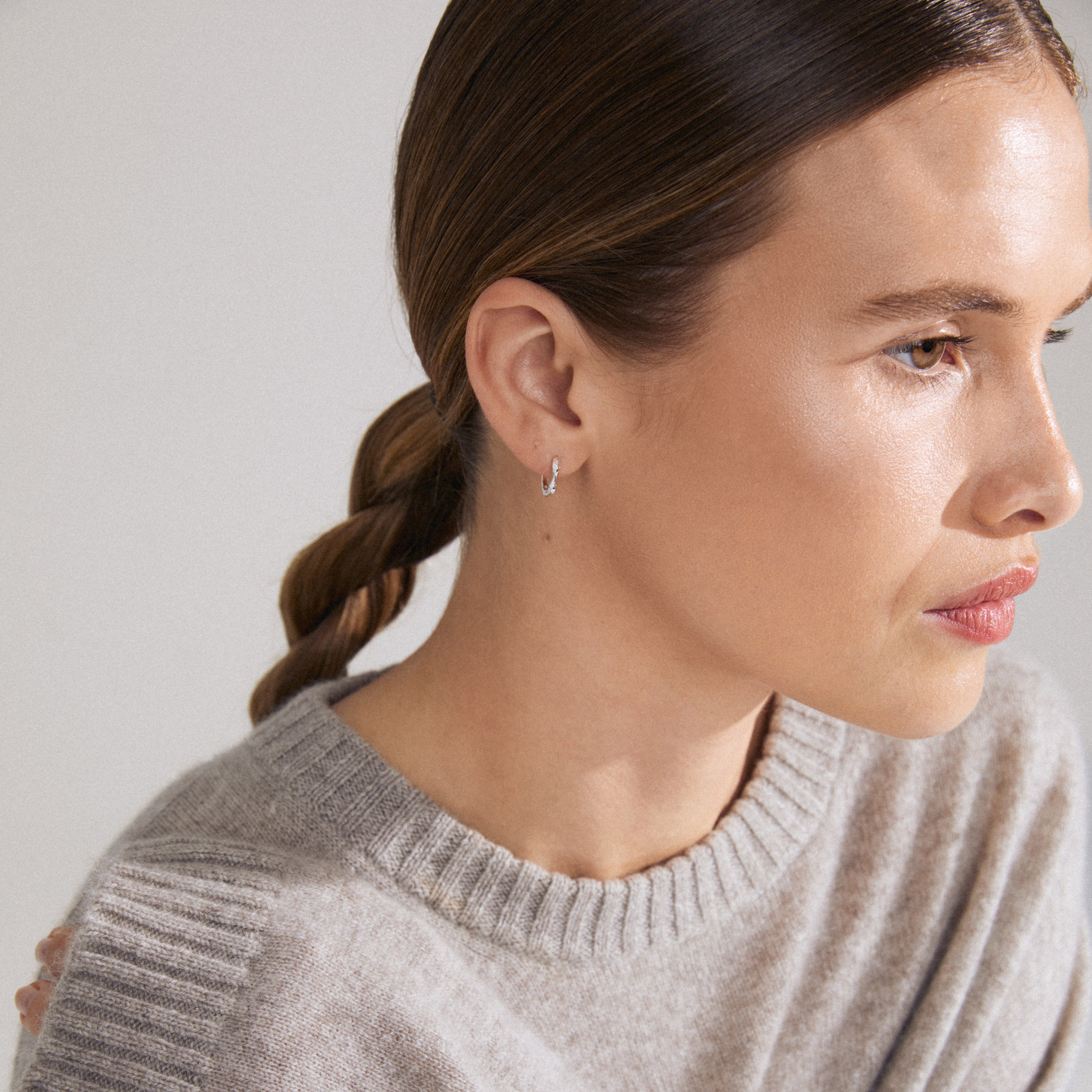 KYRA single earring silver-plated, showcased on a woman with braided hair, features a shiny, handcrafted design with an easy click clasp.