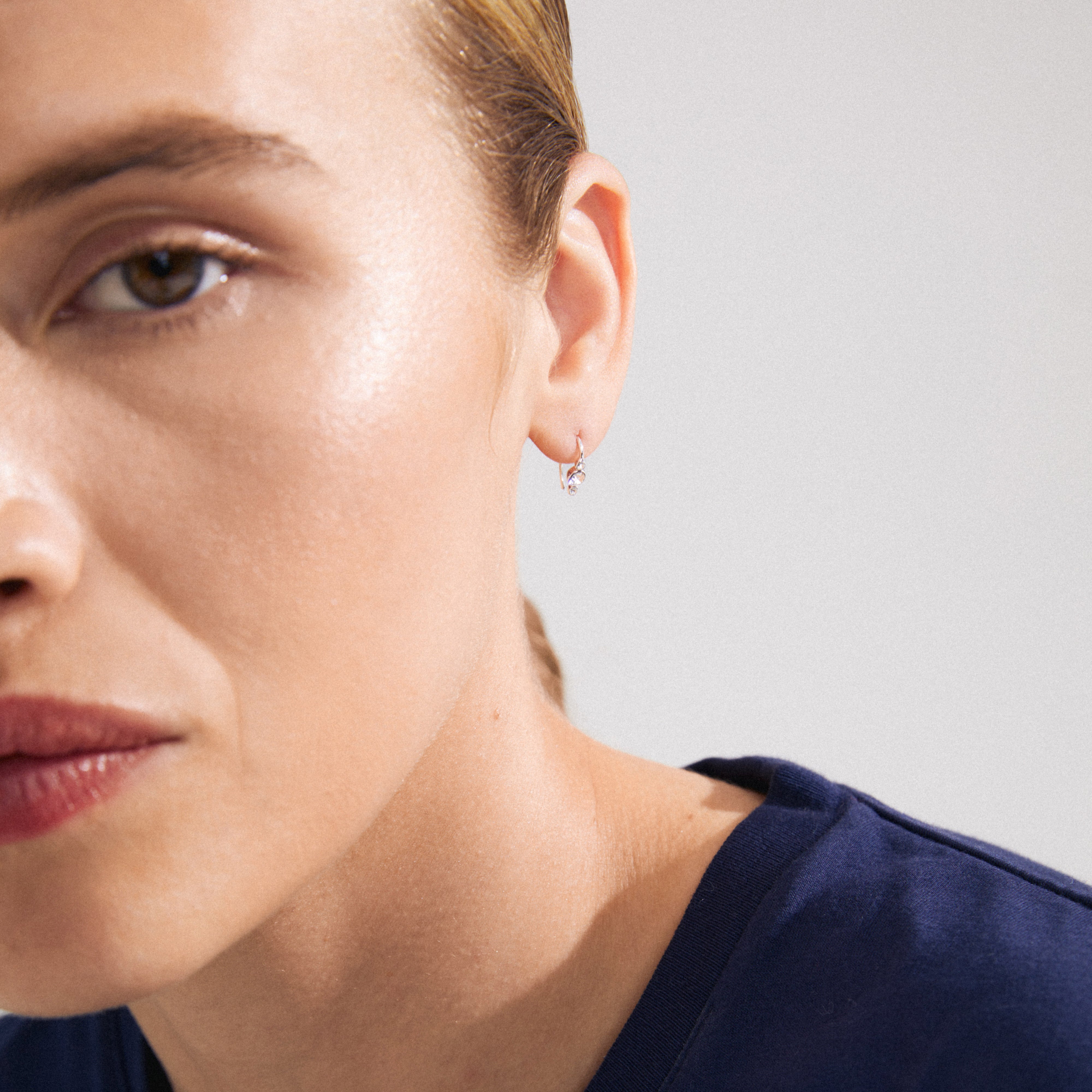 KRISTINE single earring, silver-plated, featuring three sparkling Preciosa crystals, shown worn on a woman's ear. A chic, unique piece crafted from recycled materials.